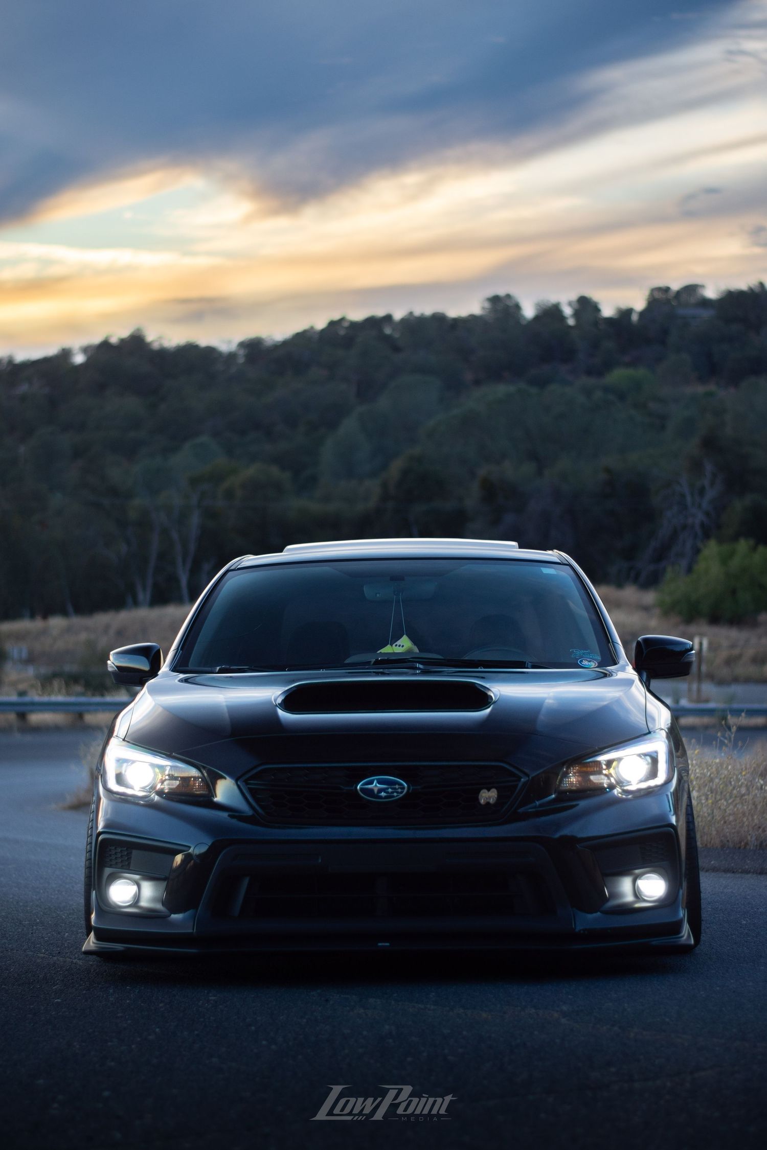 Black Subaru WRX photographed on the side of a northern California road with a blue and orange sunset behind