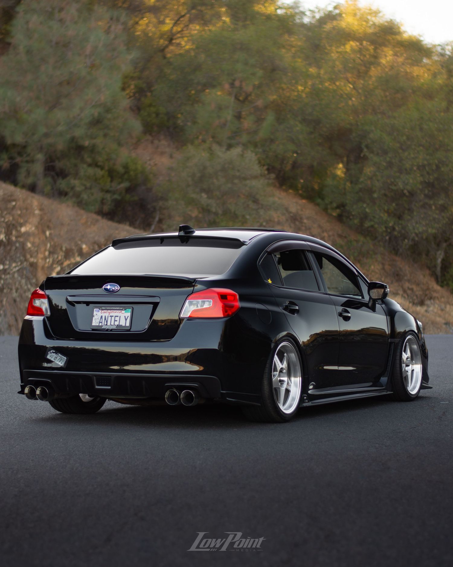 Black Subaru WRX photographed at a vista point overlooking a lake with a bridge