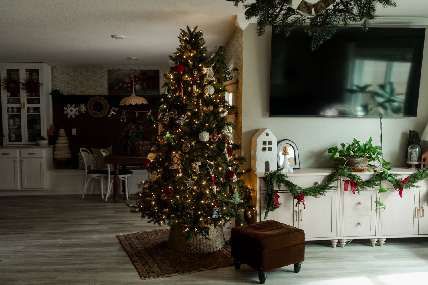 Decorated Christmas tree with lights and ornaments in a festive living room with garland and holiday decor.