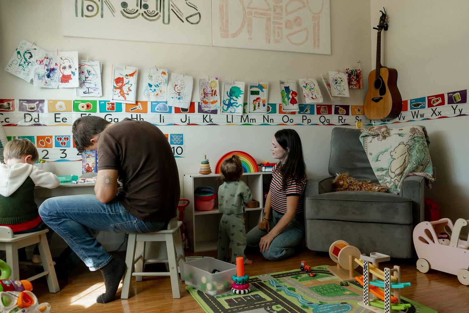 Family spending quality time together in a decorated children's playroom with alphabet wall and toys.