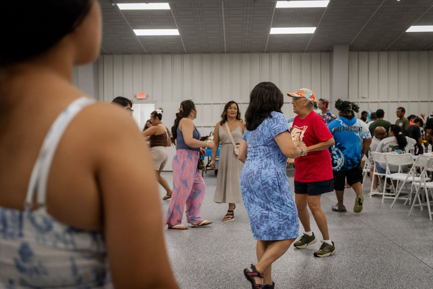 People dance together on a large floor at an indoor cultural celebration.