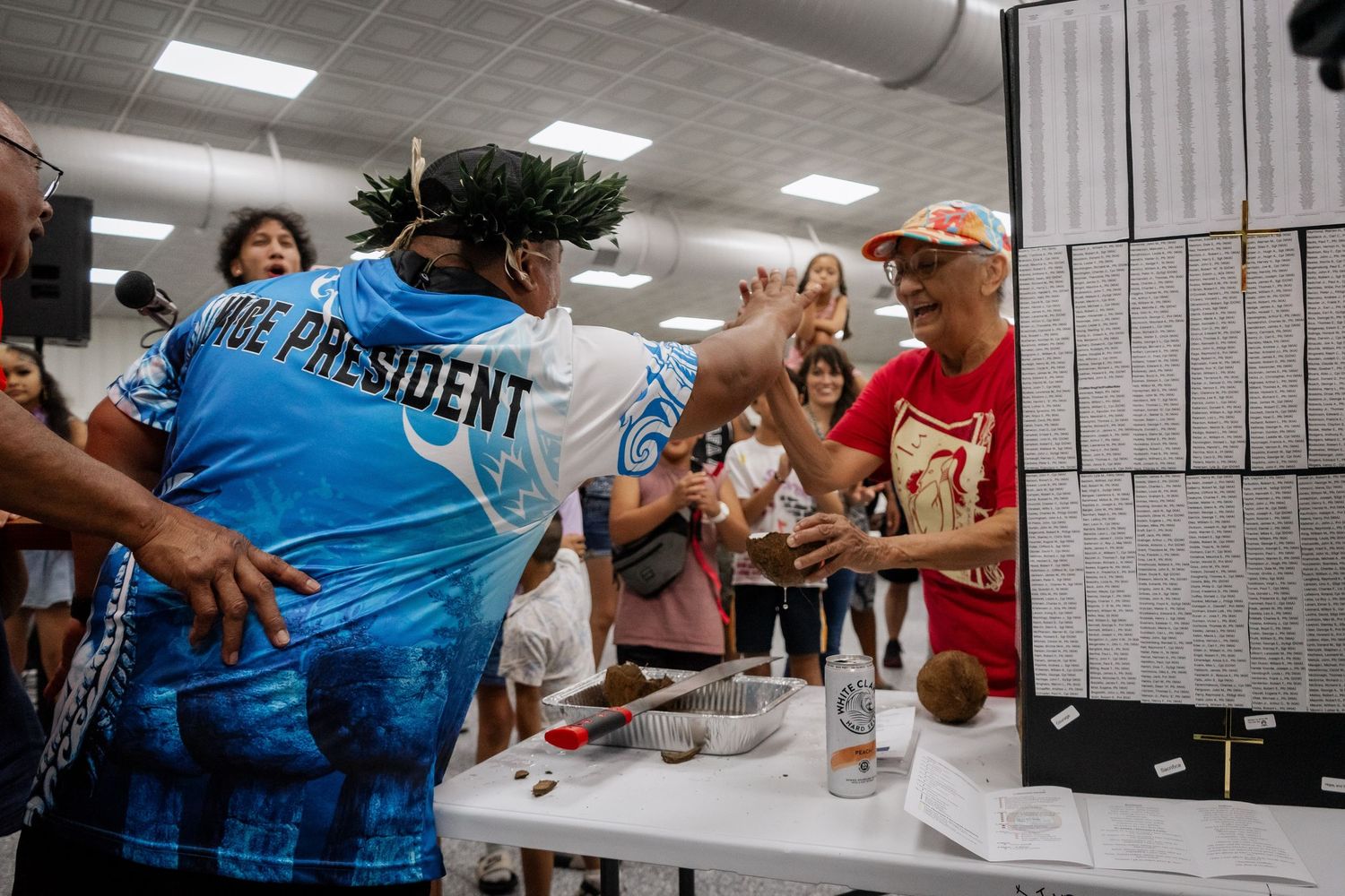 People gathered at an indoor event as a person wearing a Vice President jersey high-fives another attendee.