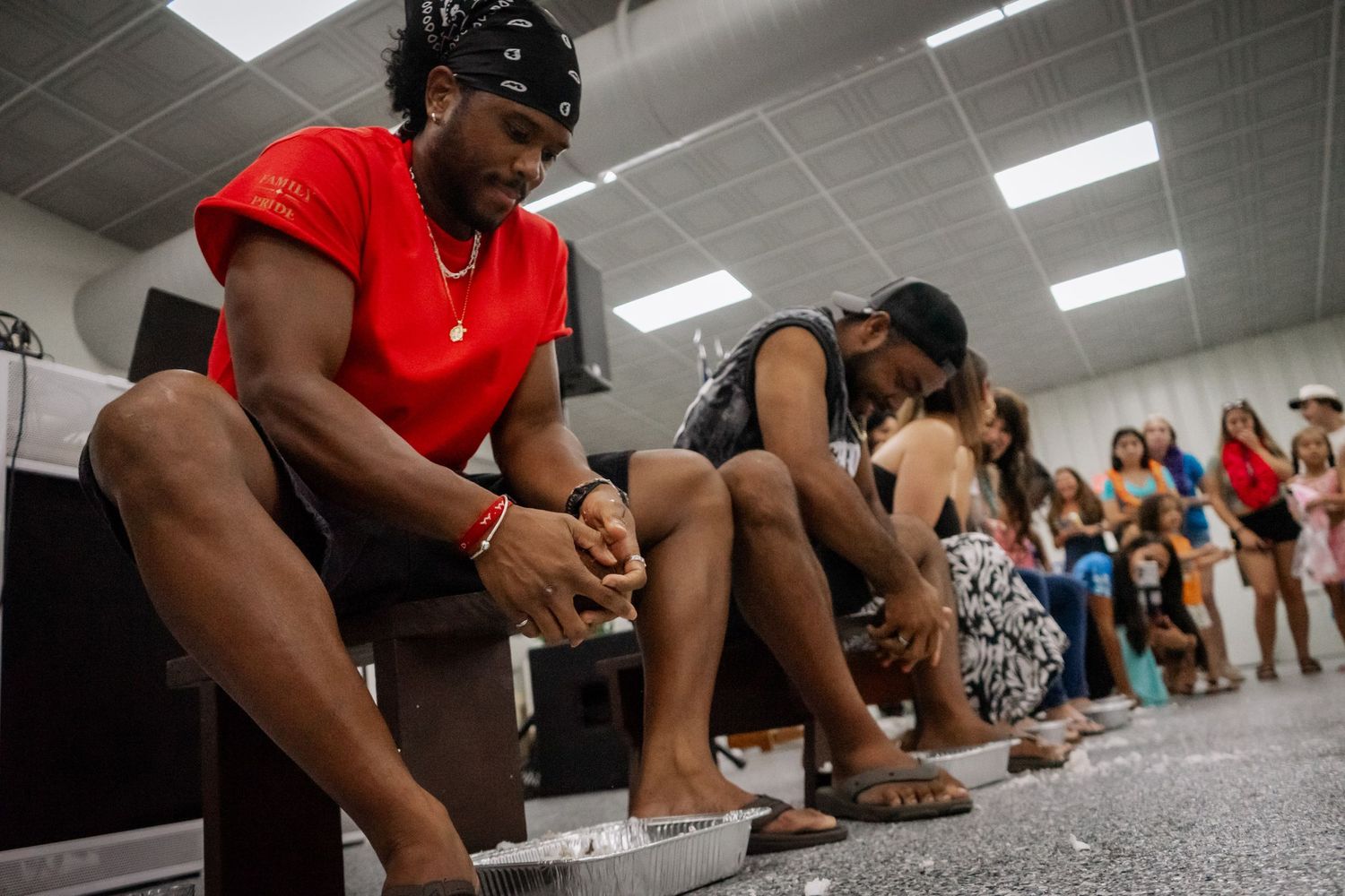 Men seated in a row participating in a foot-soaking activity at an indoor cultural event.