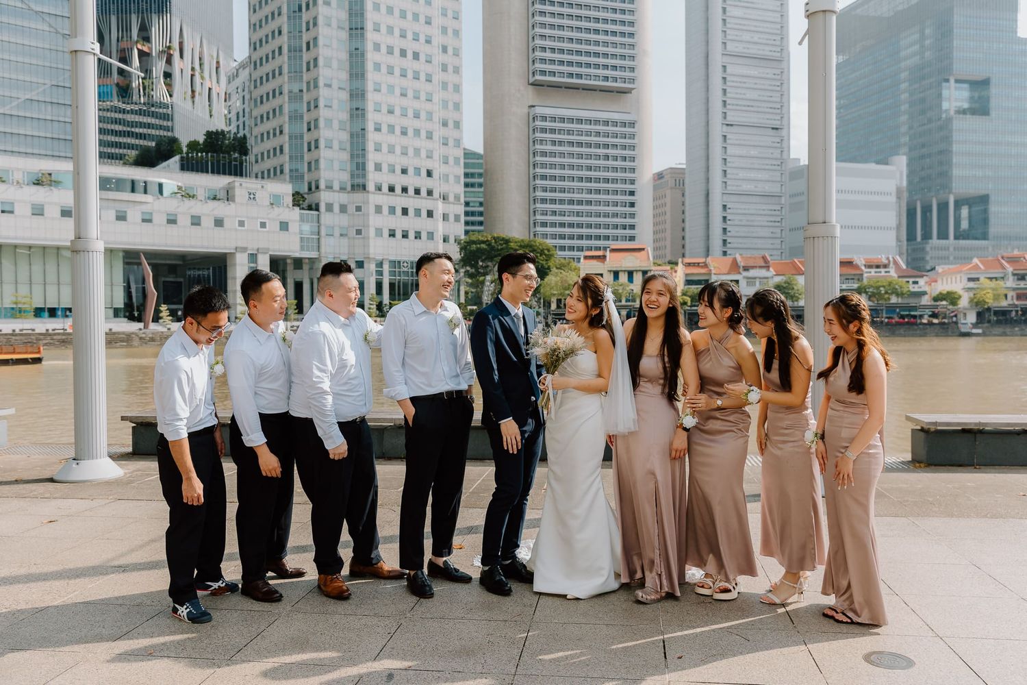 A wedding party poses together on a city rooftop with modern skyscrapers in the background.