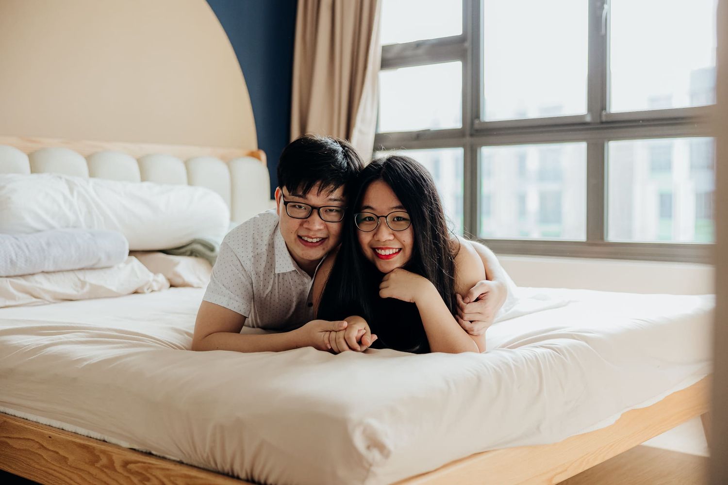 Lifestyle photography of couple relaxing on bed with natural window light streaming in.