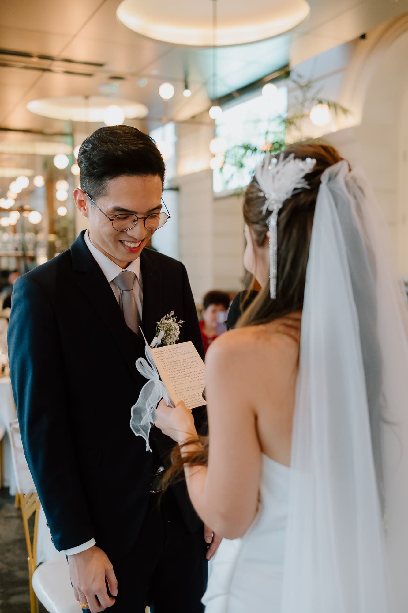 Couple exchanges vows during intimate indoor wedding ceremony with warm lighting and romantic atmosphere.