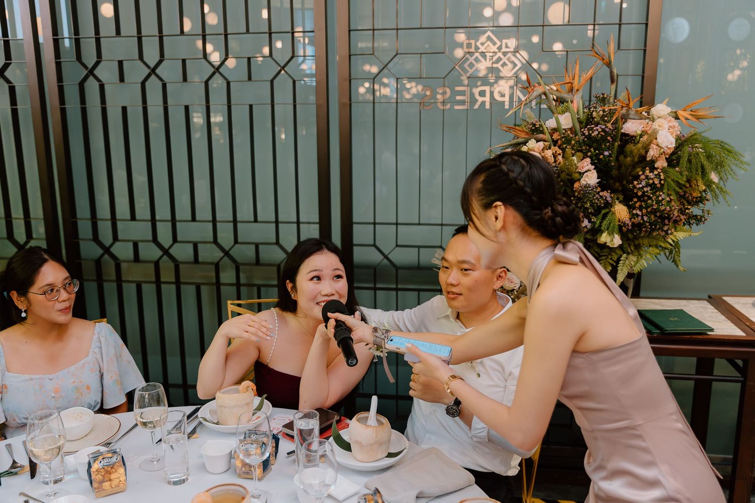 Elegant dinner party guests enjoying dessert and drinks at a beautifully decorated restaurant table.