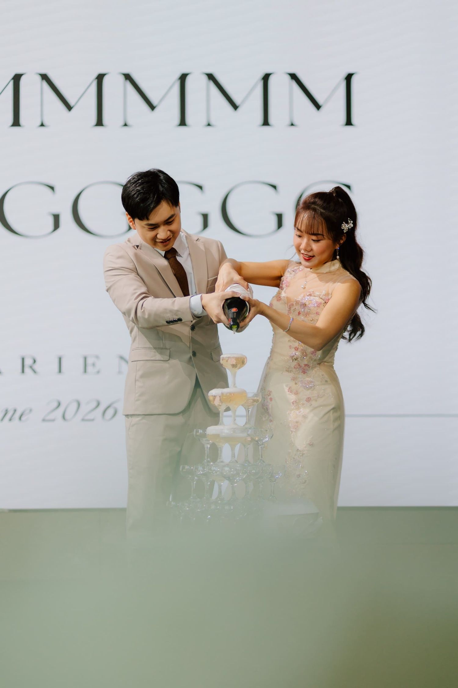 Couple pouring champagne tower at elegant wedding reception, June 2026.