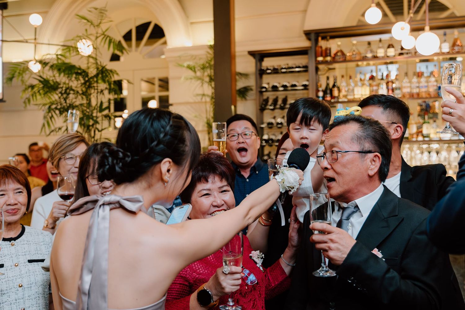 People raise glasses in a toast during what appears to be a wedding reception or celebration event.
