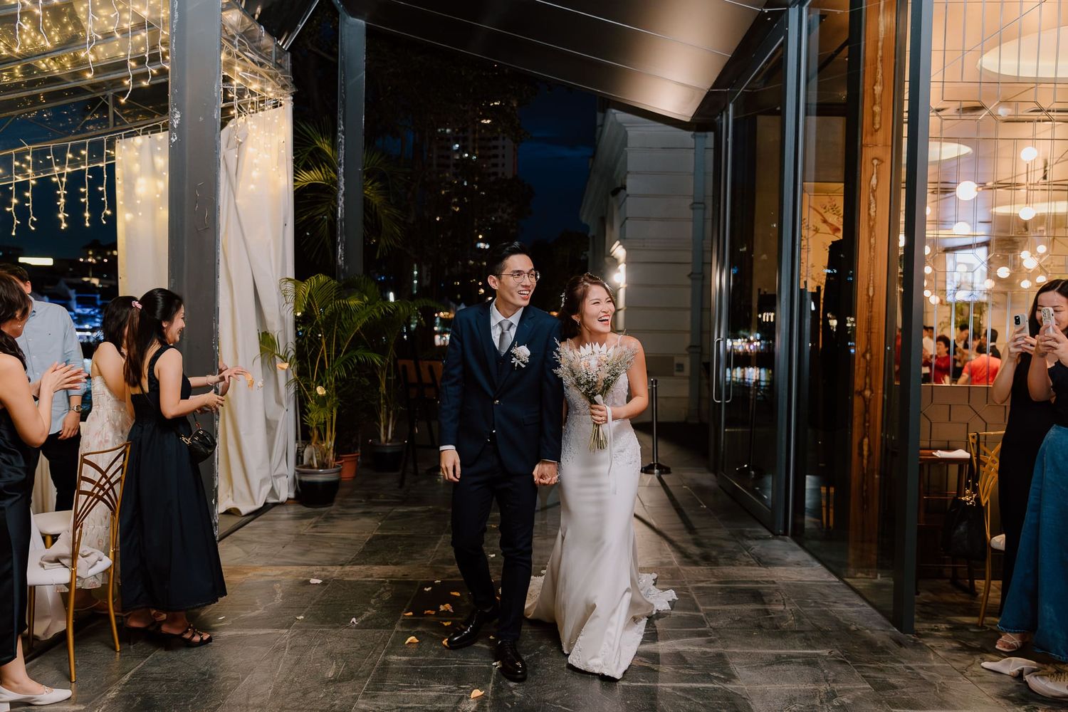 Newlyweds sharing a romantic first dance together in an elegantly lit reception venue with guests watching from the sides.