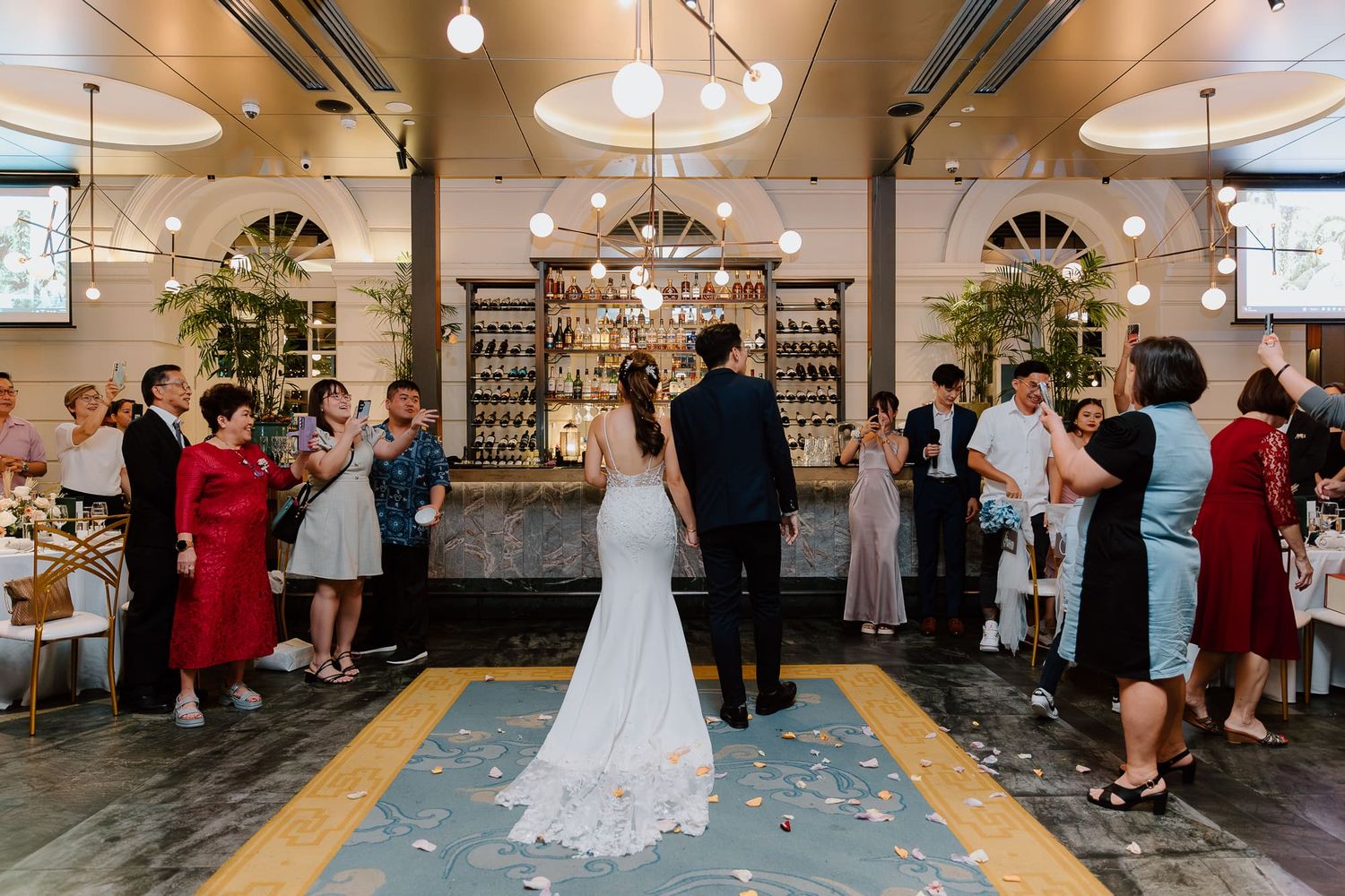 A wedding ceremony takes place in an industrial-chic venue with exposed beams and hanging lights as guests look on.