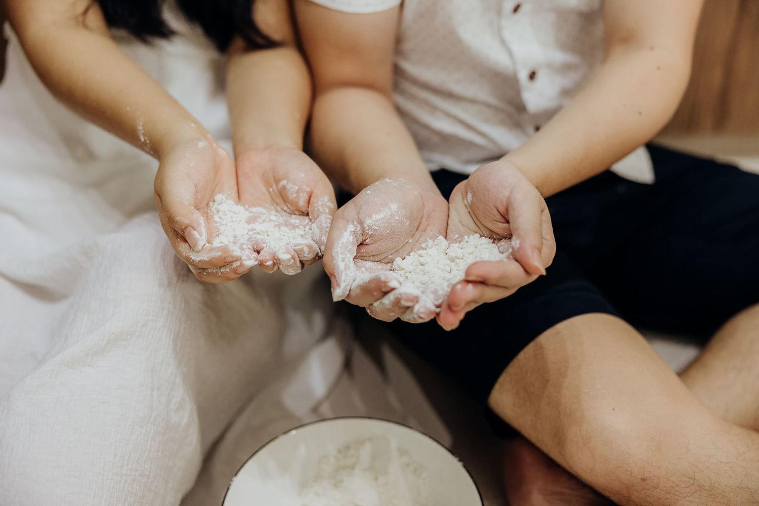 Hands working with flour or dough in a kitchen setting.