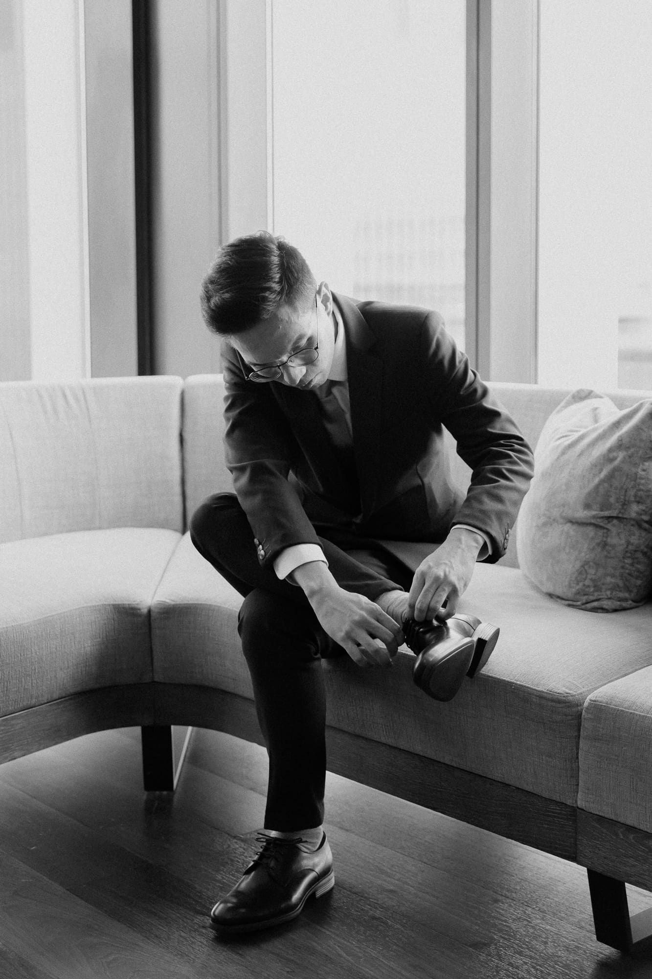A black and white series showing the stages of a person falling off a white couch onto a dark wooden floor.