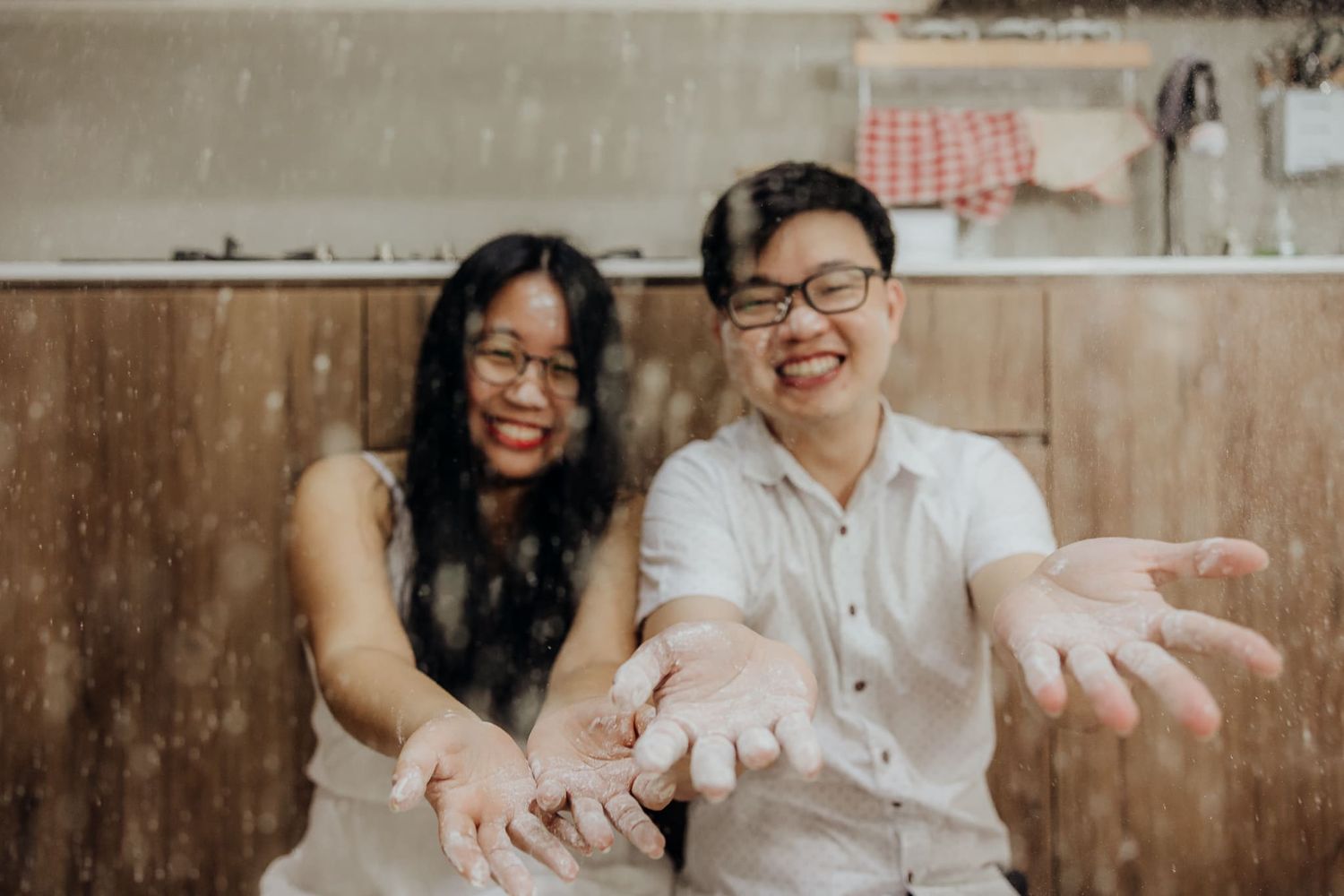 Two people laughing and playing with flour while baking in the kitchen.