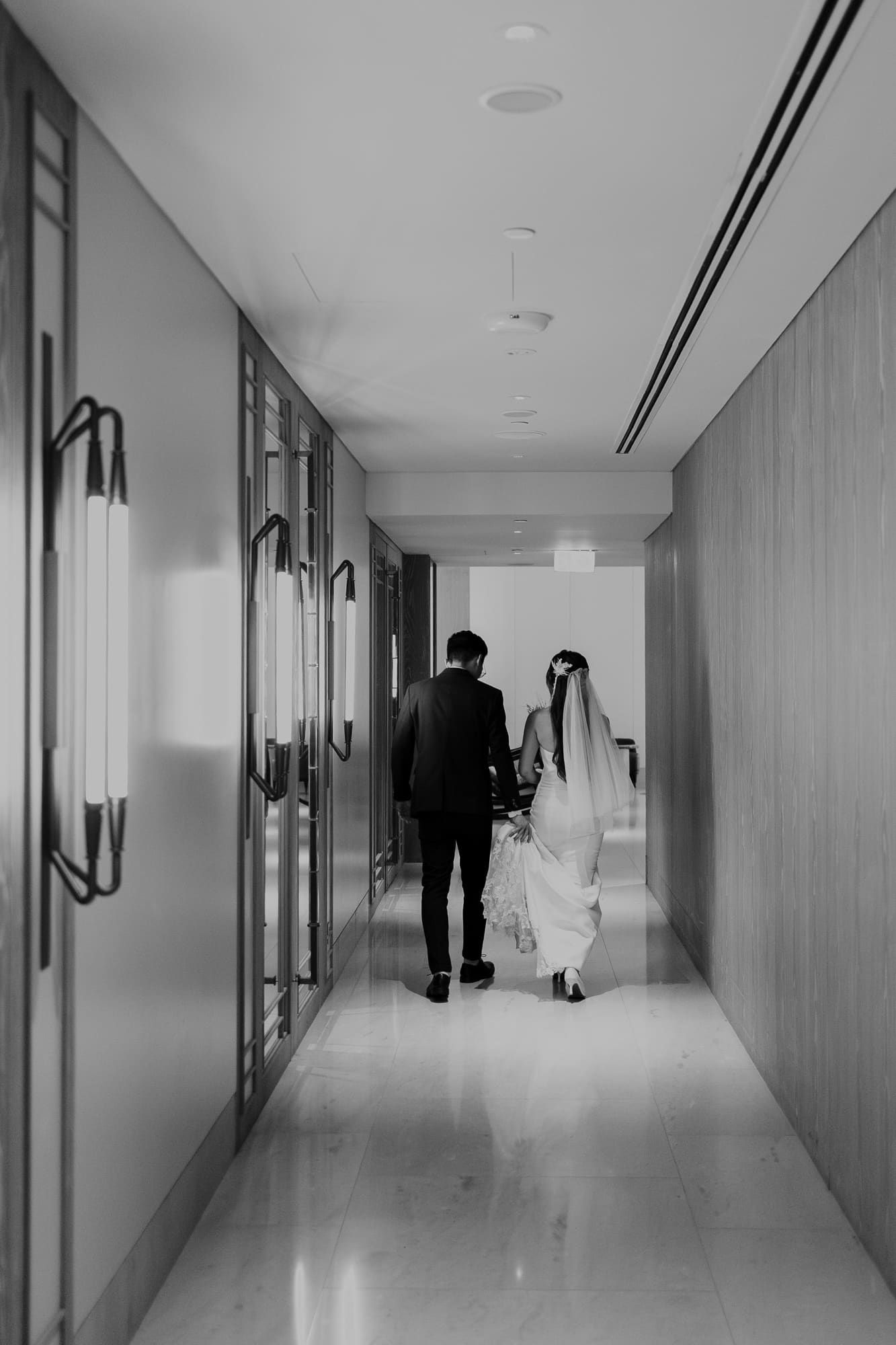 Eerie black and white photo of a dimly lit hallway with shadowy figures and reflective floors.