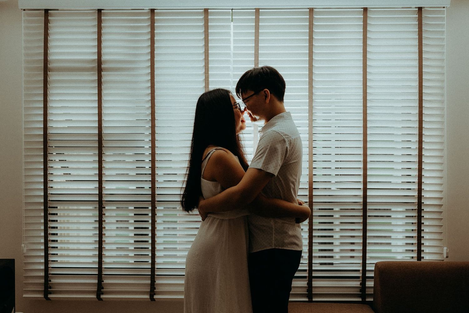 Silhouettes against window blinds in a bright interior setting.