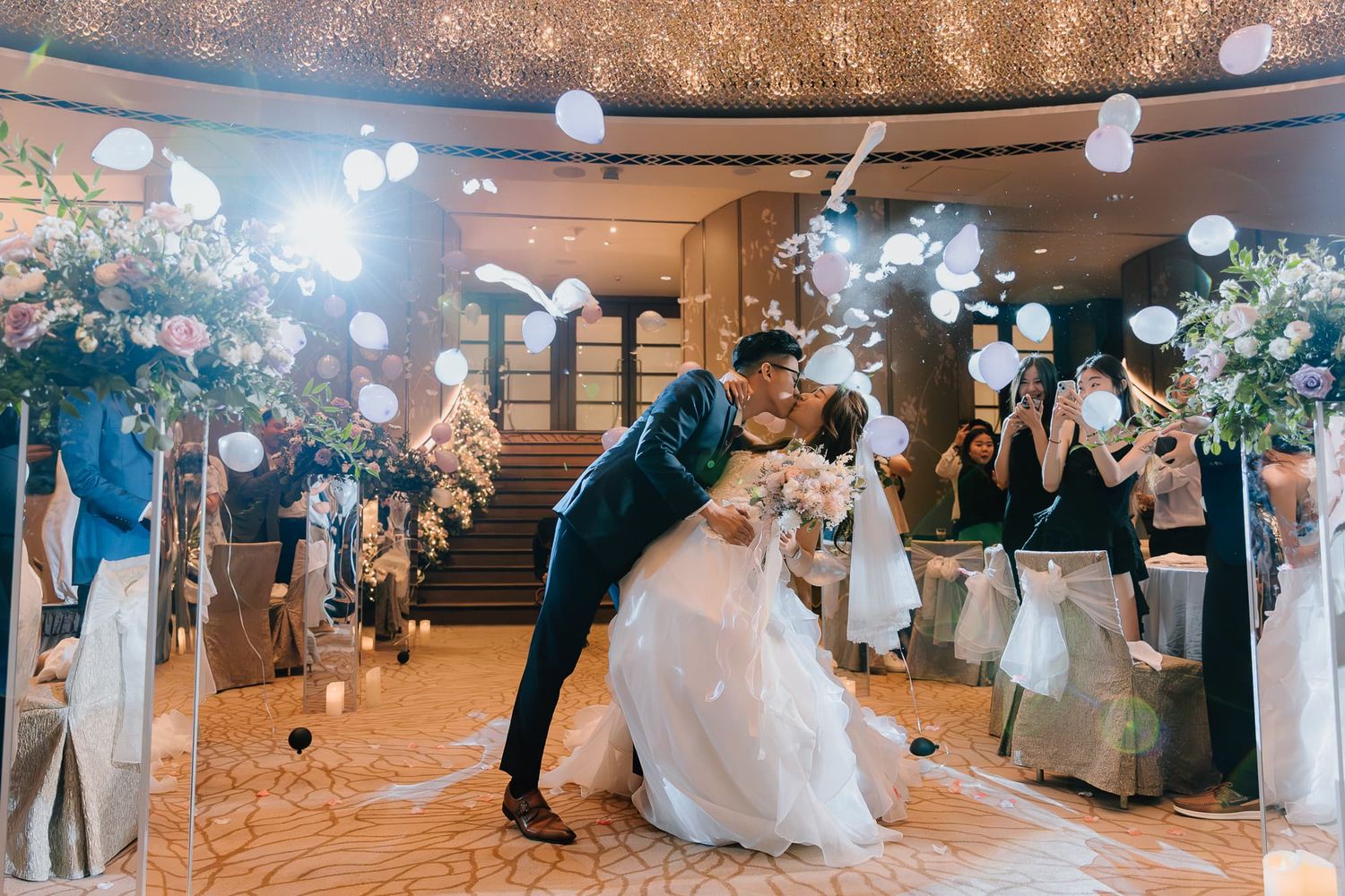 Panoramic view of a wedding reception with white lanterns and floral arrangements.