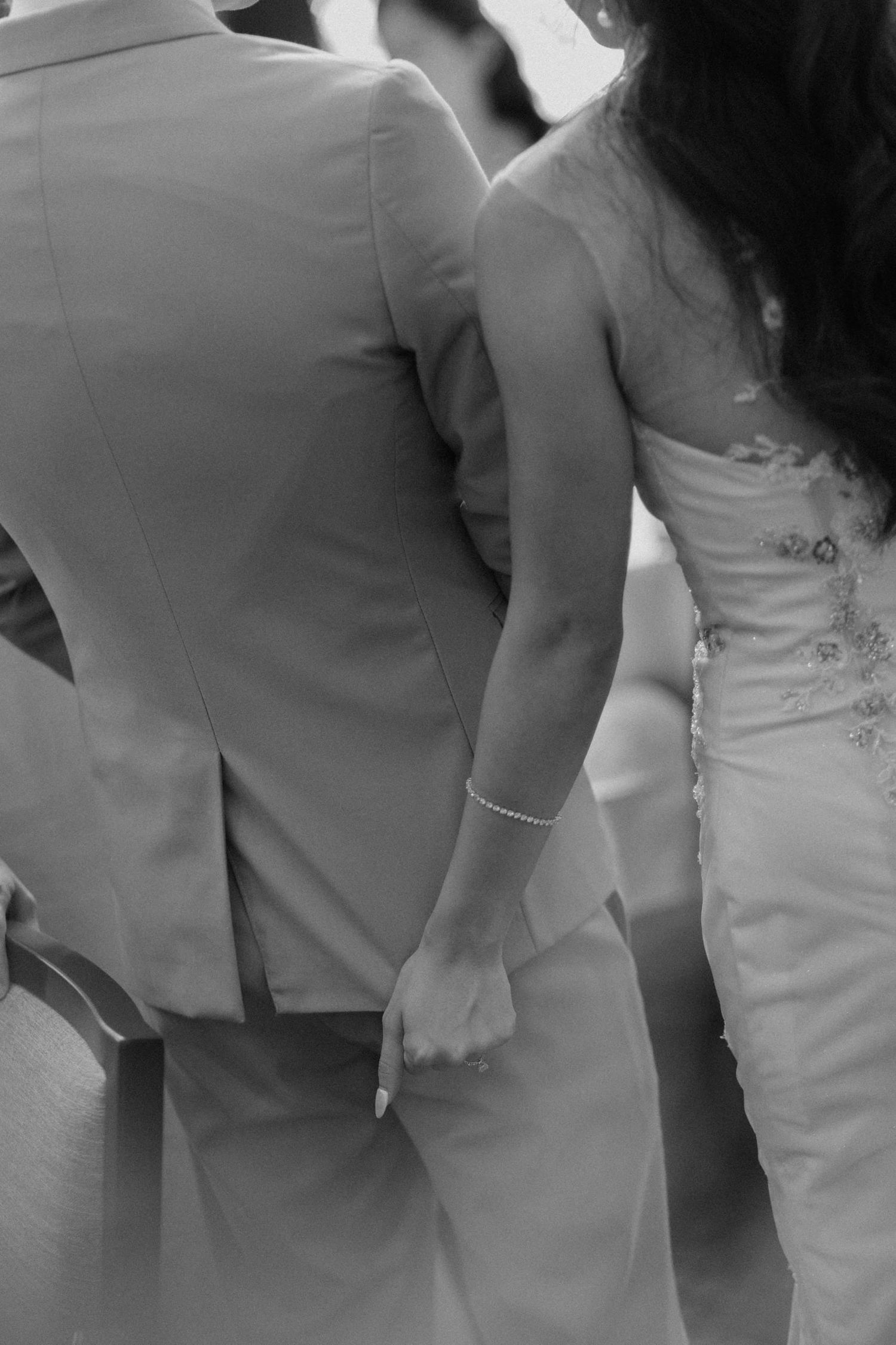 Black and white photo of a bride and groom holding hands at their wedding ceremony.
