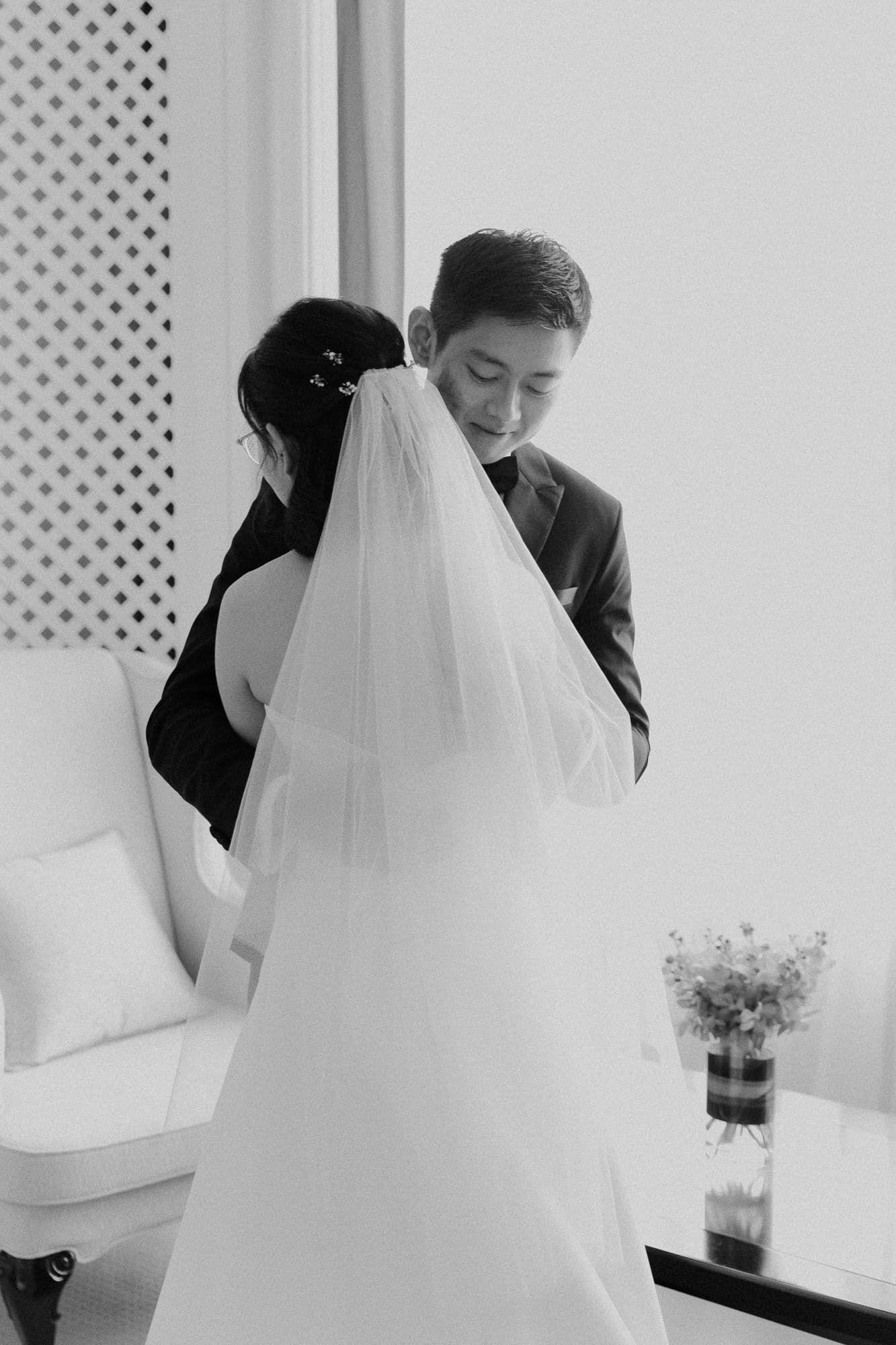 Black and white intimate wedding moment captured against white lattice backdrop.