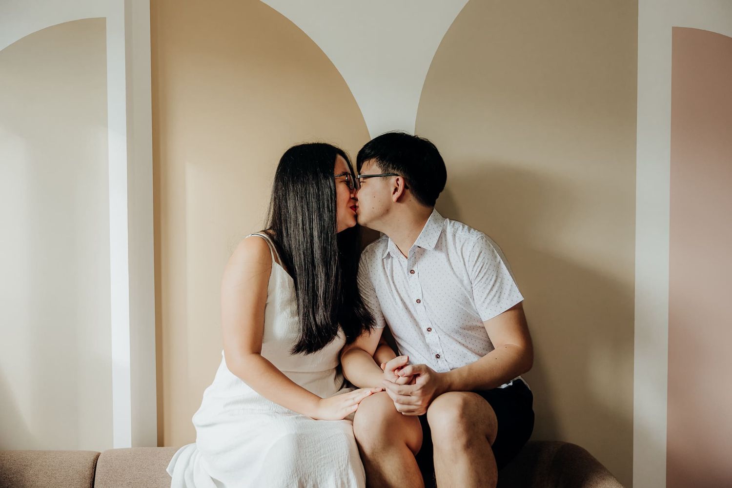 Sweet couple sharing affectionate moments on a couch in warm lighting.