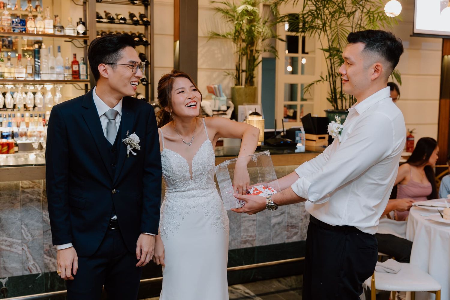 Three people share a joyful moment and laughter together during a celebration at an elegant bar venue.