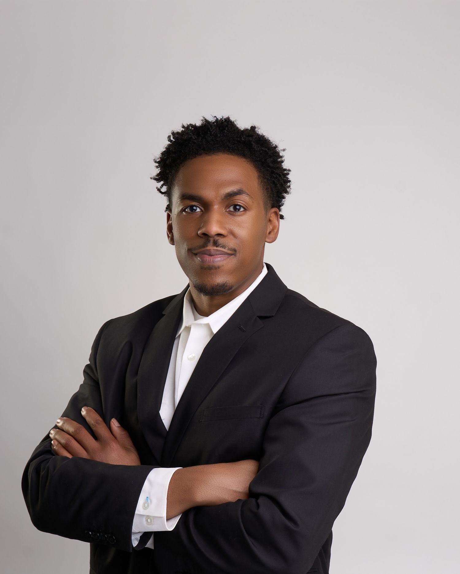 Professional young Black man in black suit with arms crossed posing for a business headshot in Bryan college station Texas