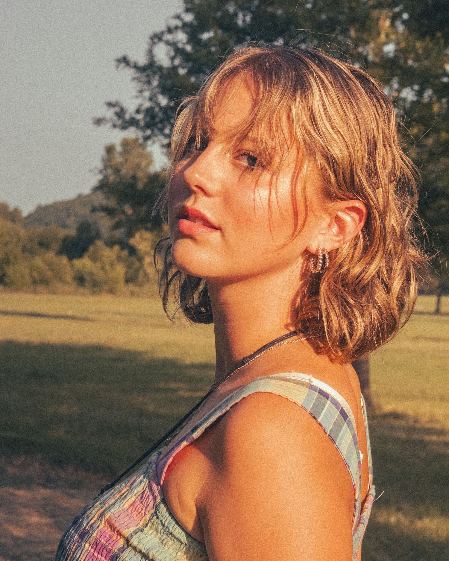 Caroline standing in a field tilting her head up looking at the camera.