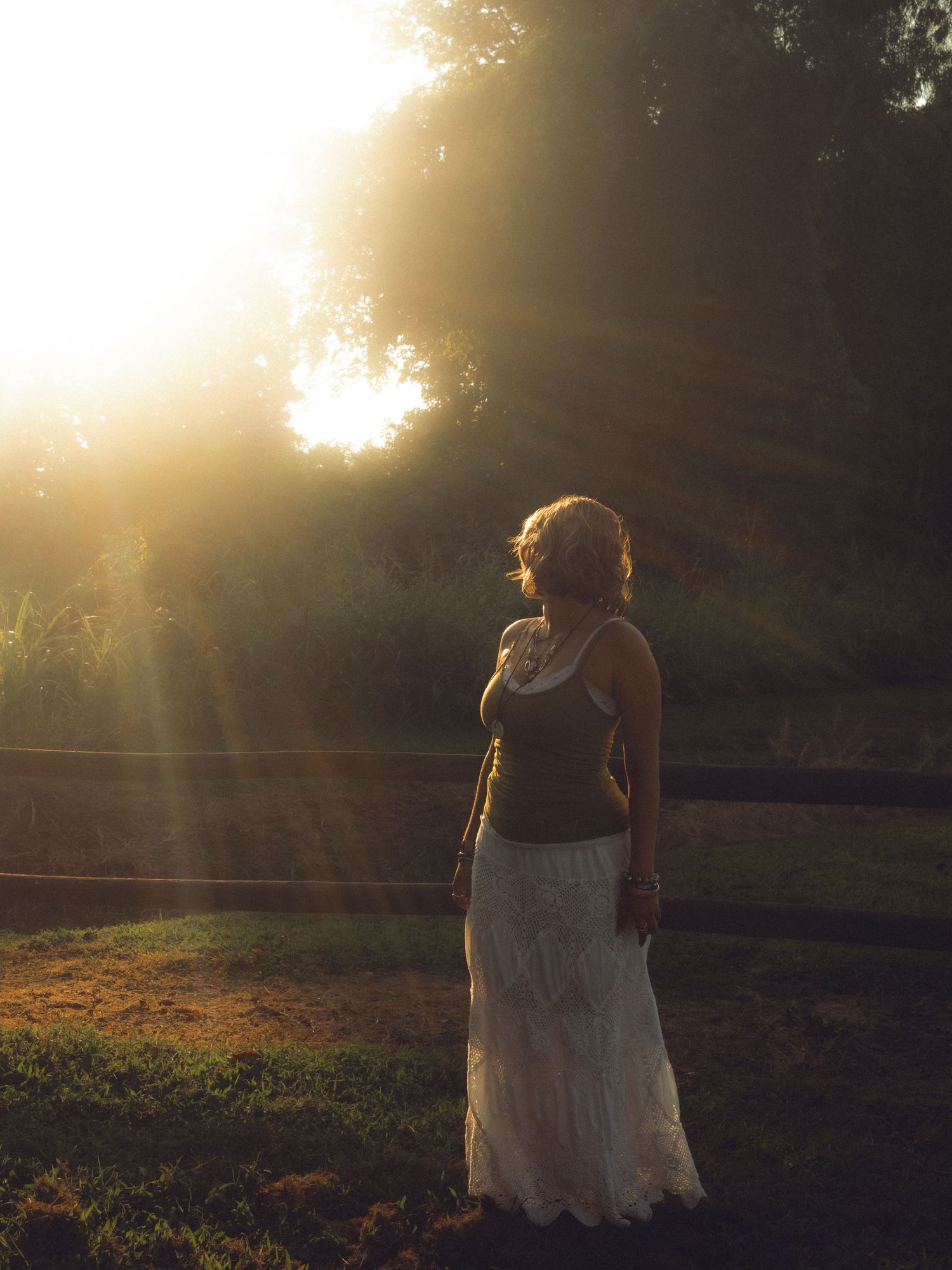 Caroling standing by a fence looking off into the sun.