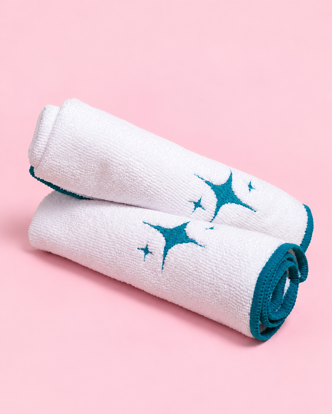 A studio product photo of towels with a light pink backdrop.