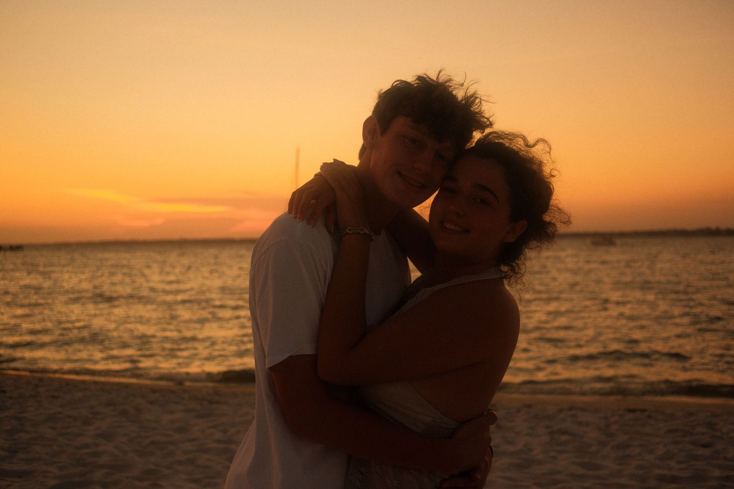 Sawyer and Fiona hugging on the beach together at sunset.