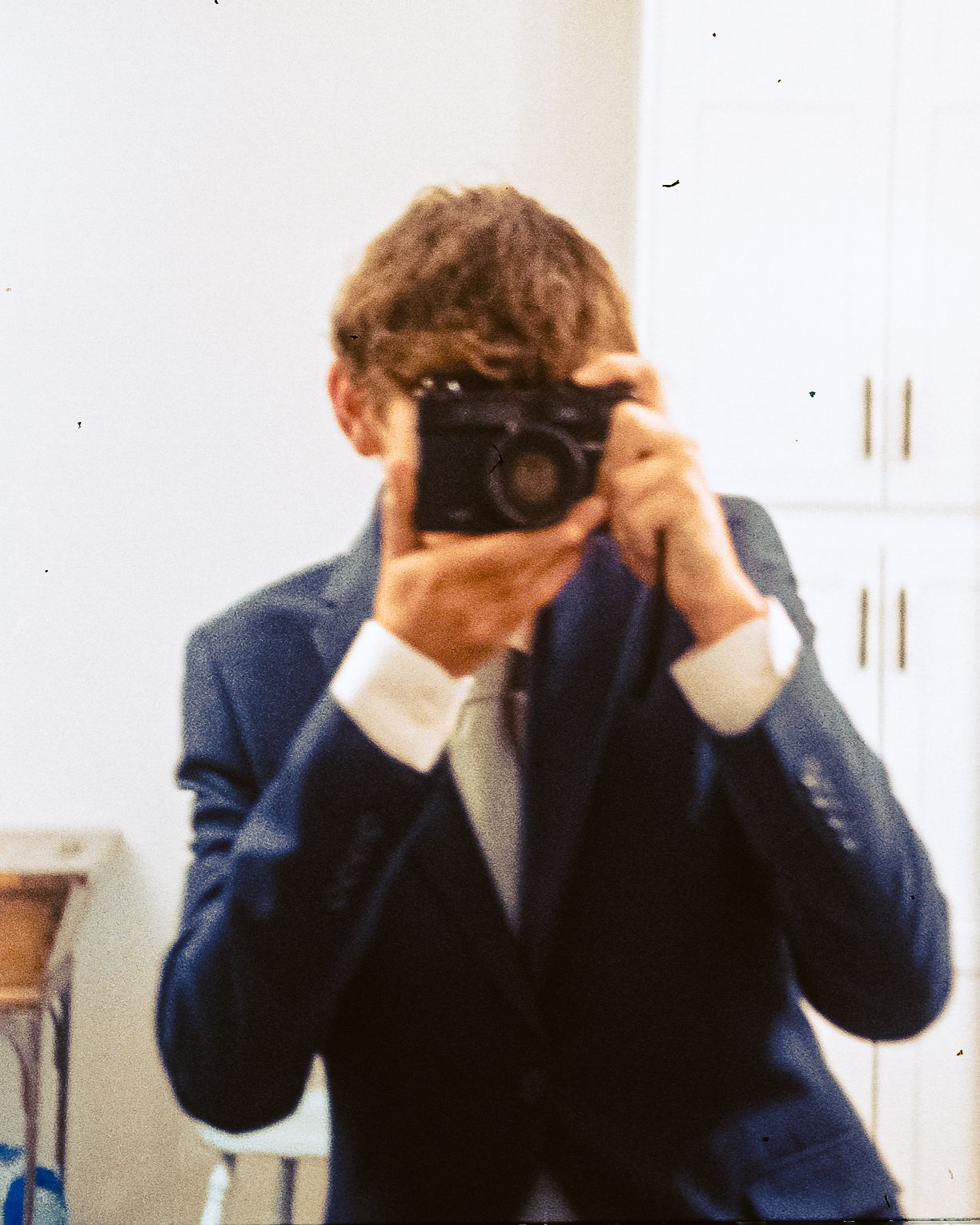 Me in a suit with a Yashica Electro 35 film camera held up to a mirror.