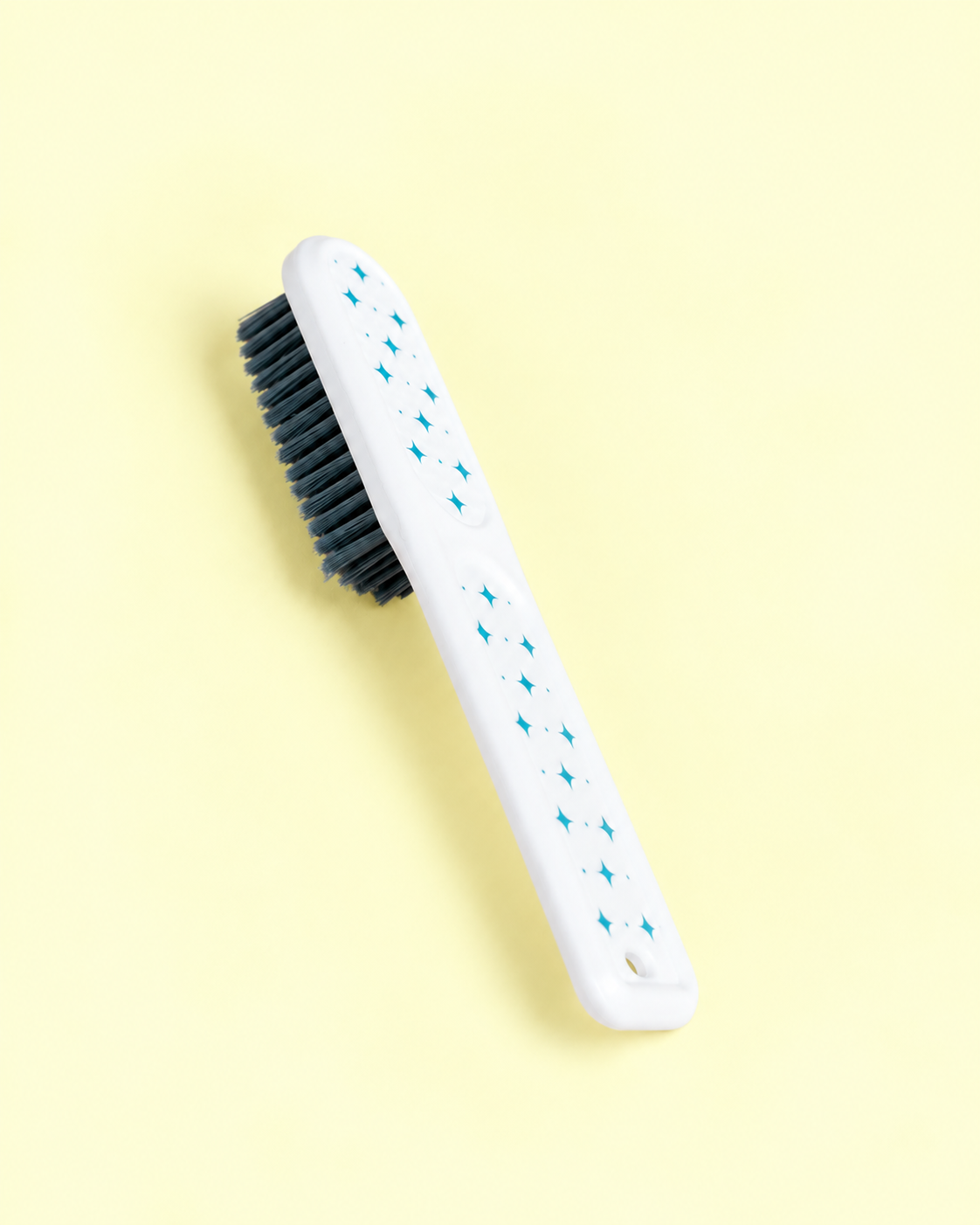 A studio product photo of a brush with a yellow backdrop.