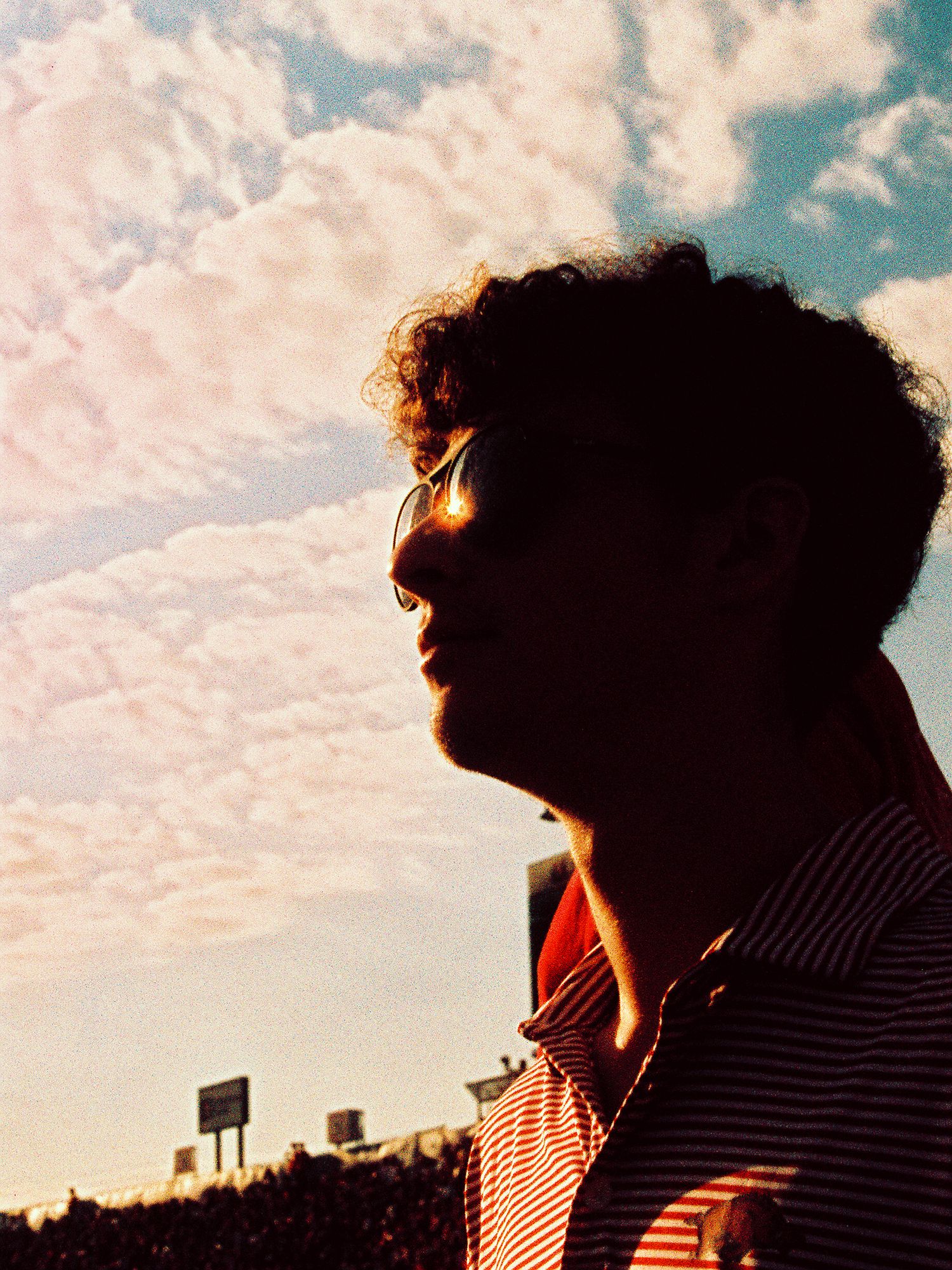 Side profile silhouette of a man with the sun reflecting into his glasses.