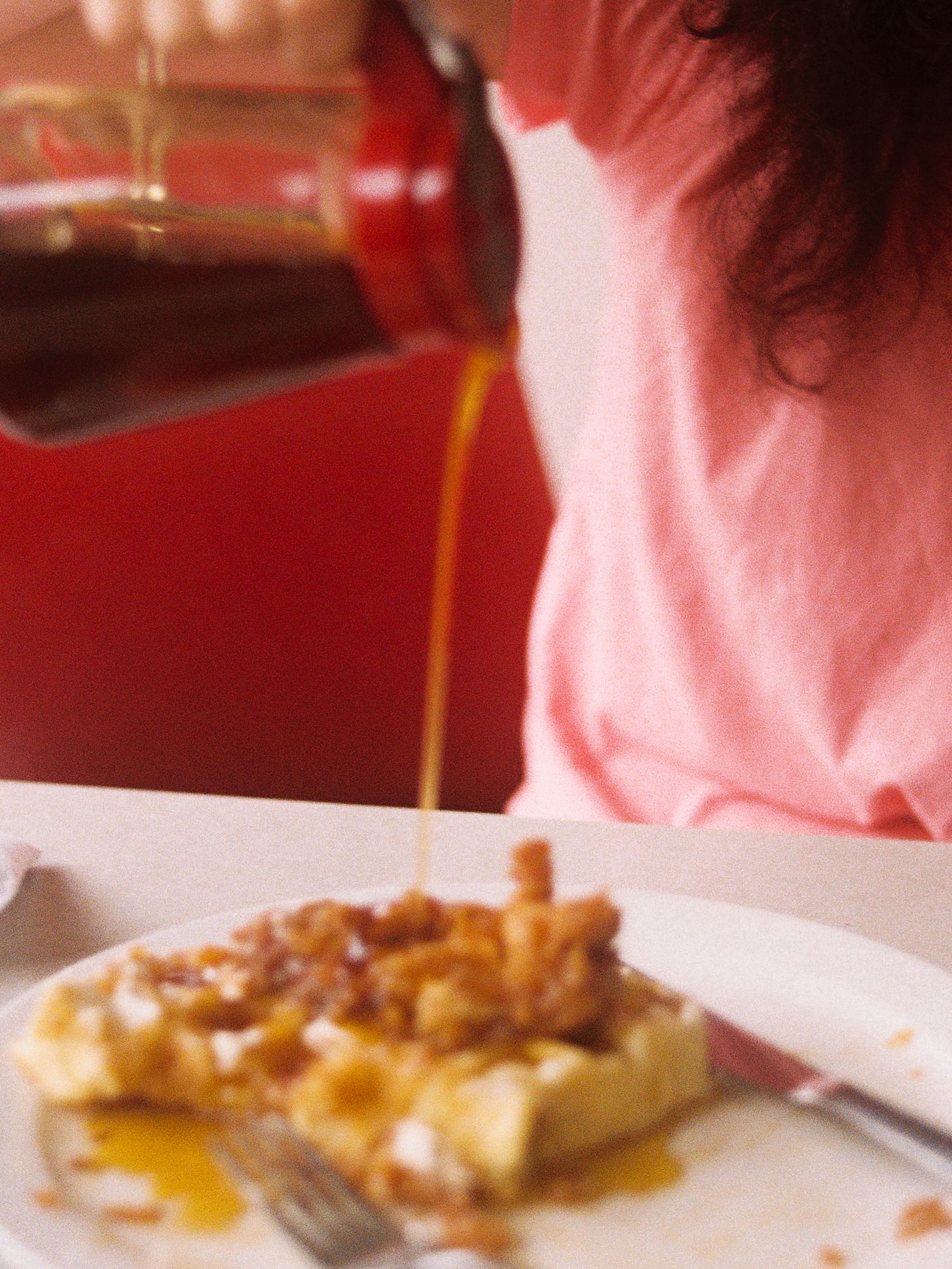 Syrup being poured onto At The Corner's chicken and waffles.
