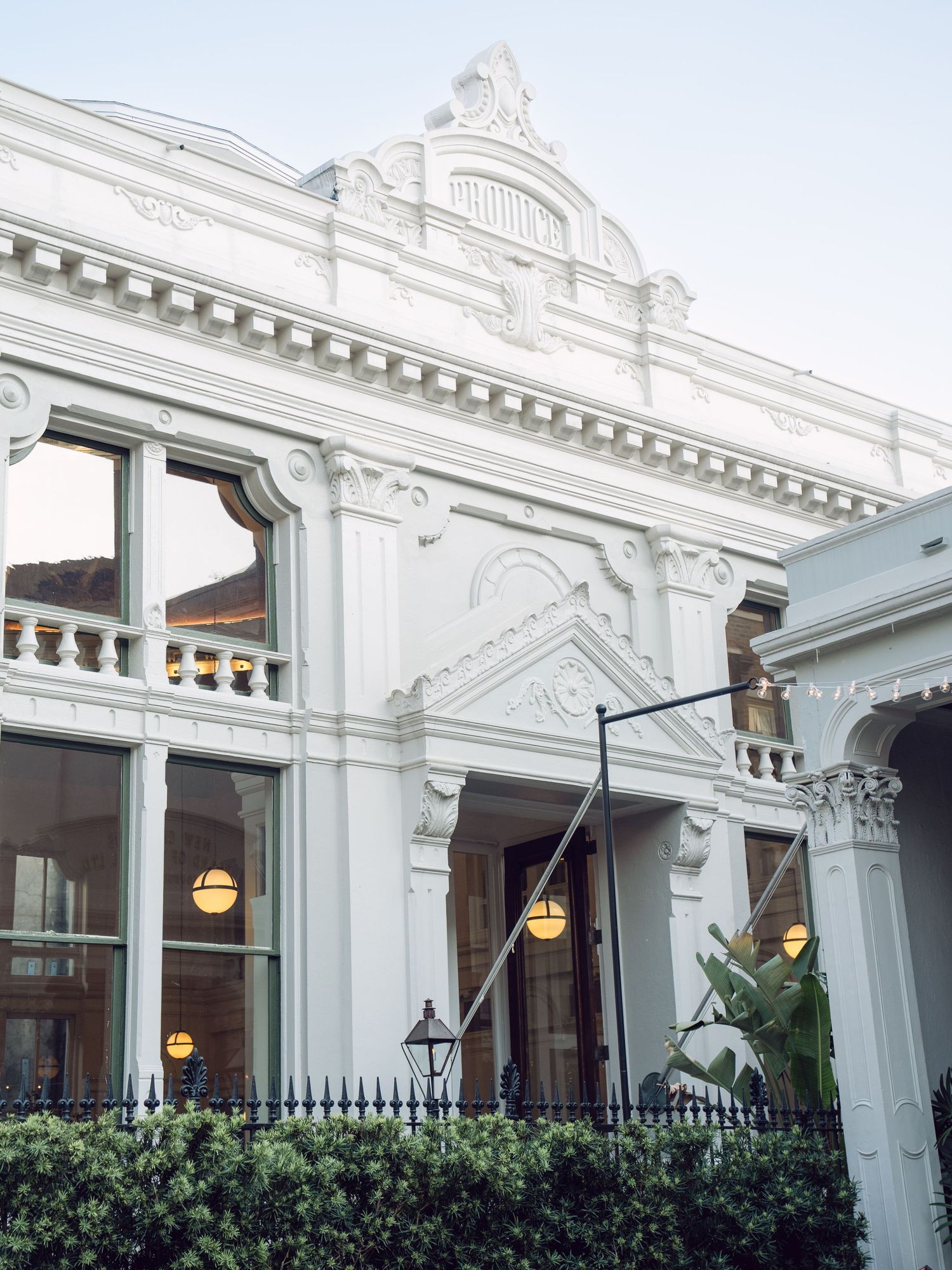 Elegant white neoclassical wedding venue exterior with ornate architectural details and glowing lanterns at dusk.