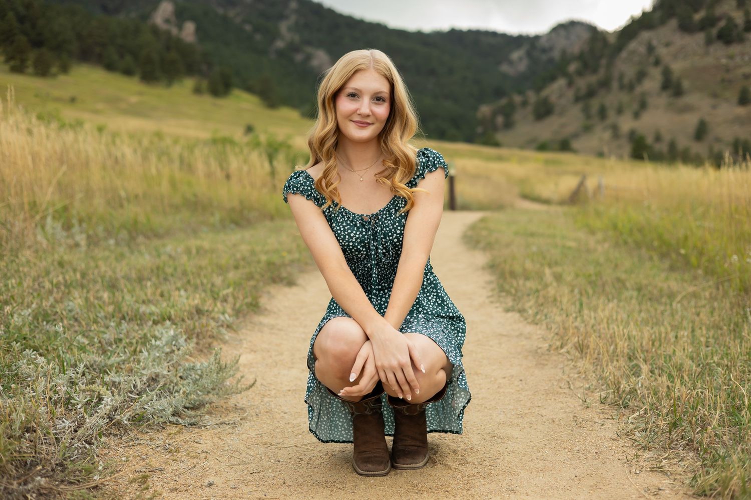 Casual outdoor portrait session on dirt path with mountain scenery.