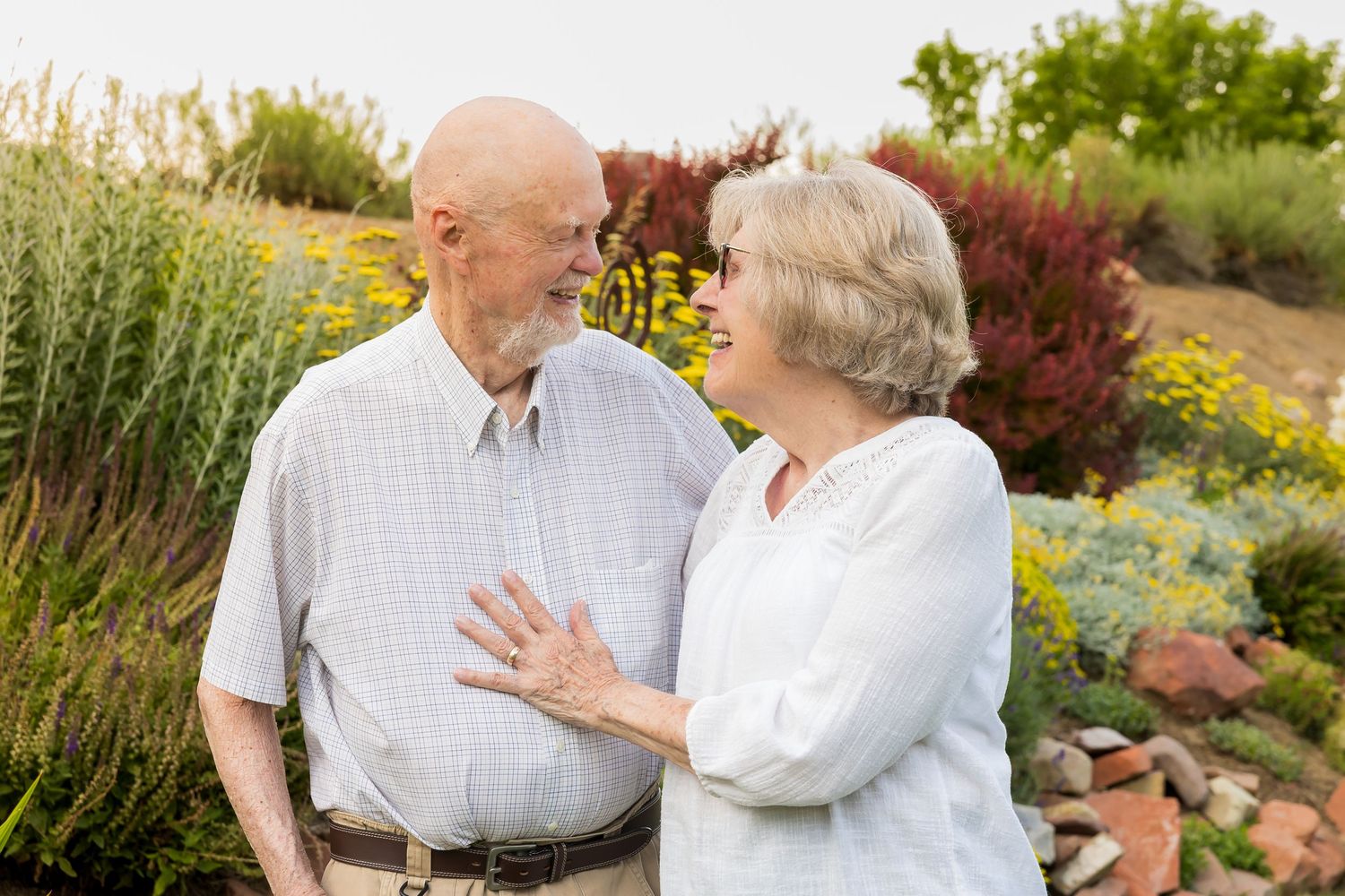 Elderly couple sharing tender moments together in a garden setting.