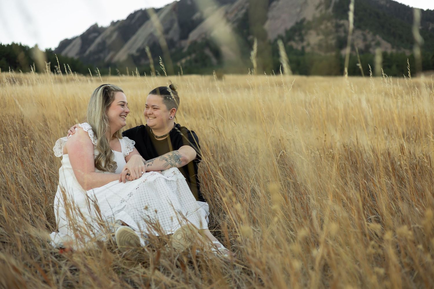 Romantic photoshoot in a golden wheat field with mountains in the background.