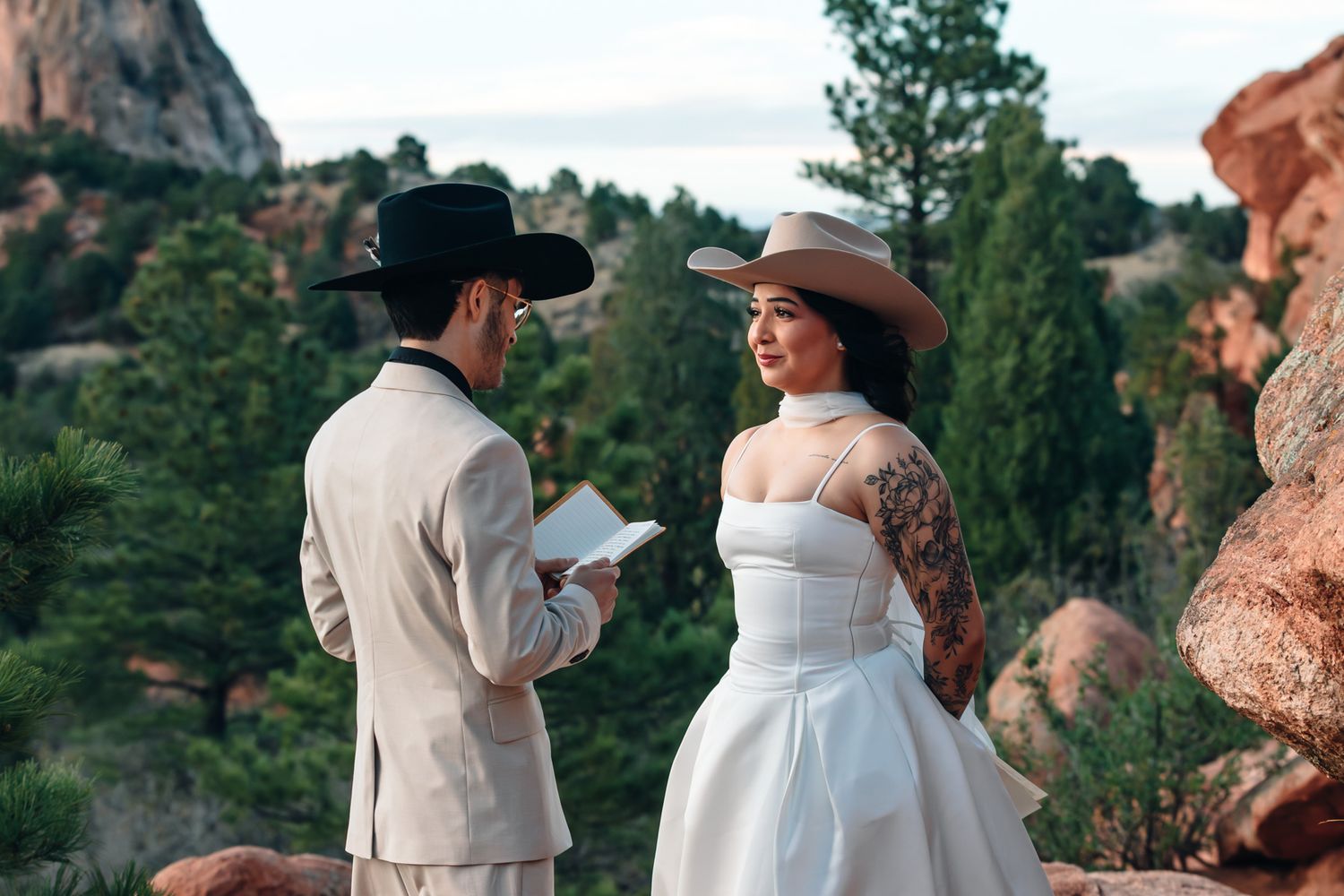 Couple in cowboy hats exchanging vows outdoors at a rocky Colorado wedding elopement site.