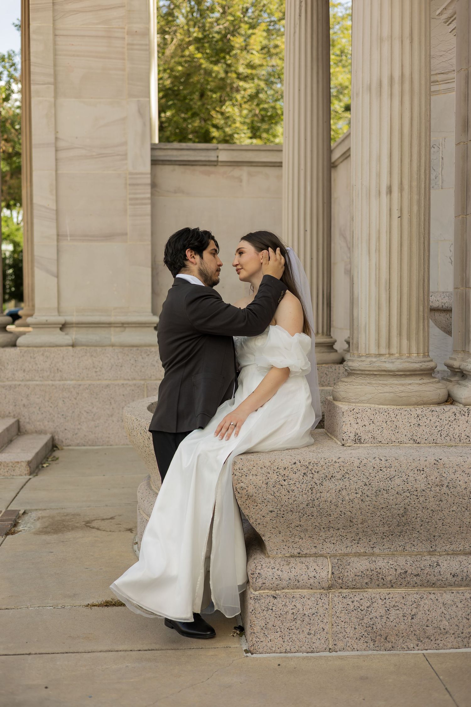 Wedding couple sharing romantic moments among classical stone columns.