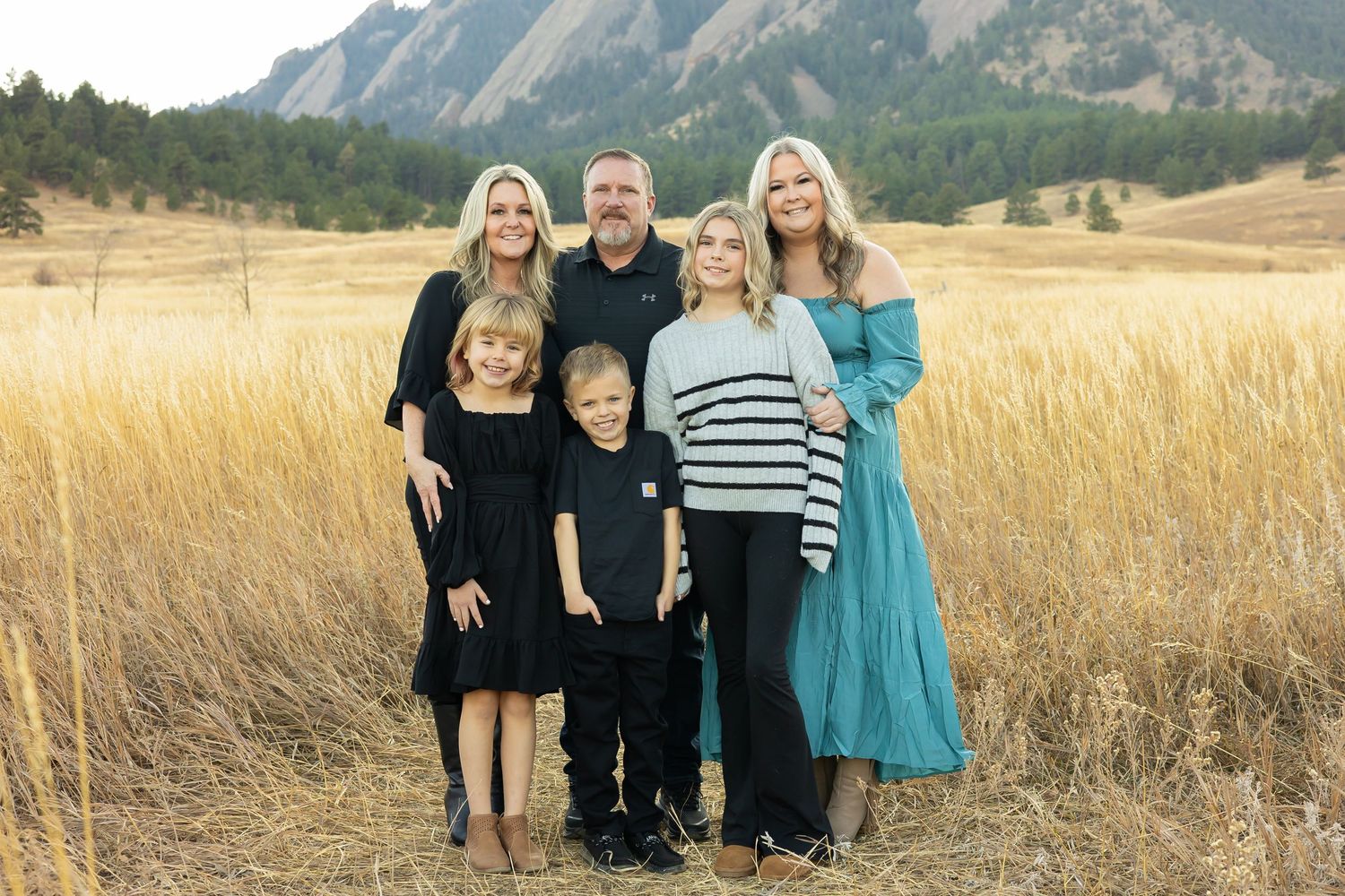 A family group portrait taken in front of the Flatirons mountains during golden hour.