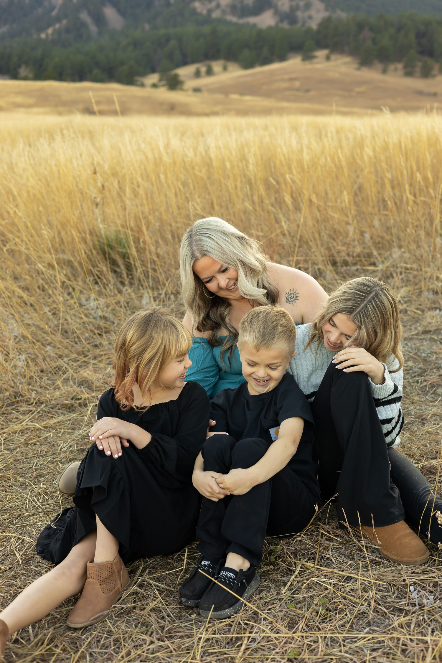 Family members lying together in a grassy field with mountains visible in the distance.