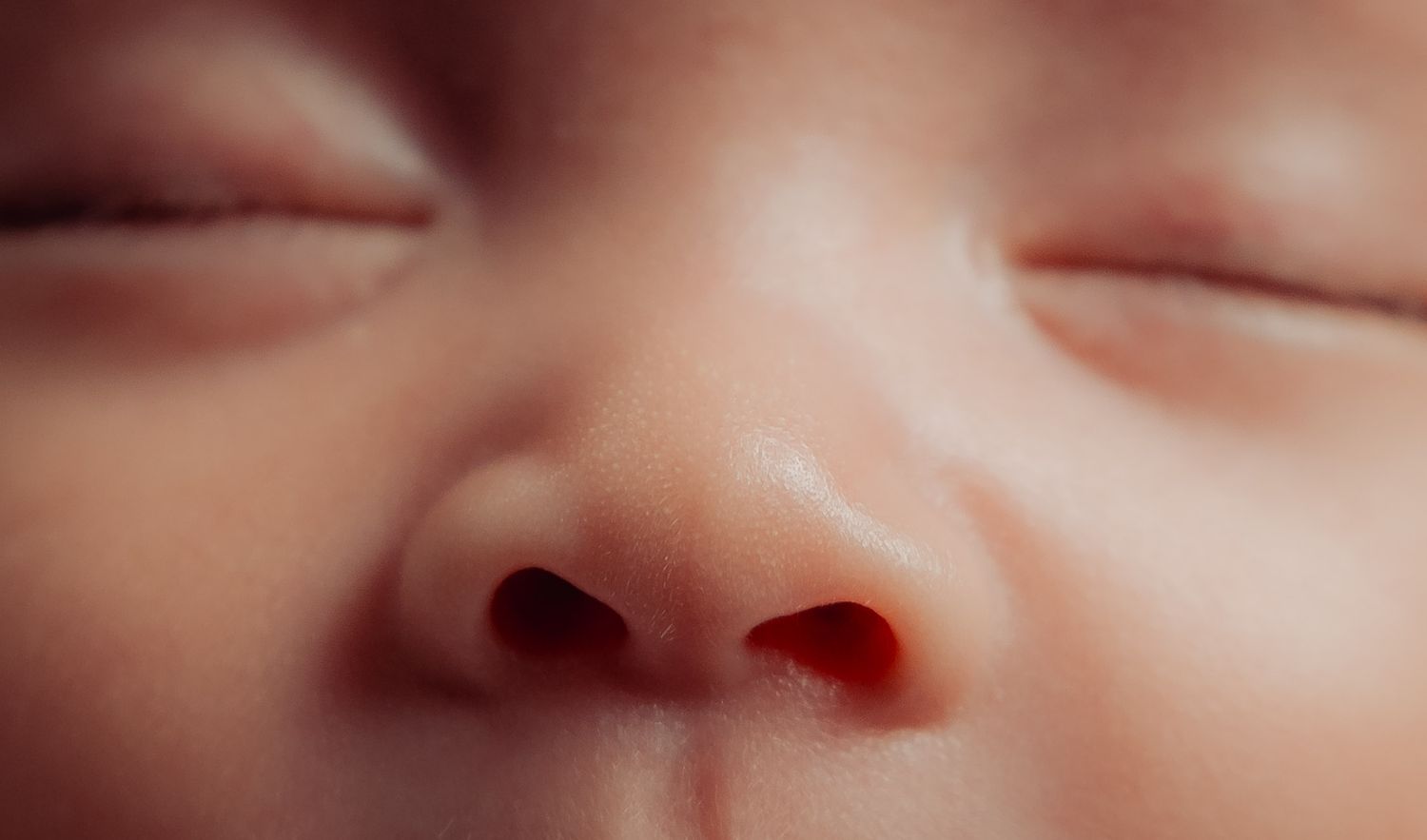 Close-up macro shot of a baby's facial features in warm tones.