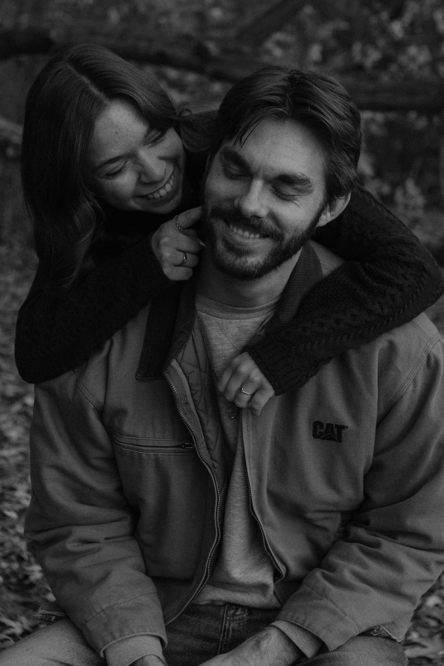 Candid black and white photo of couple laughing together outdoors.