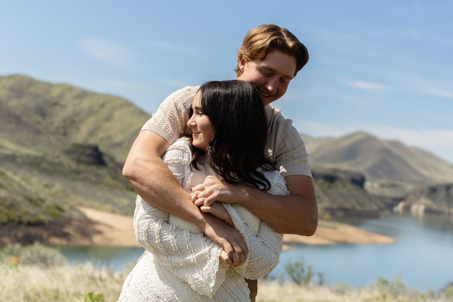 Romantic couple shares tender moments during outdoor photo session near a mountain lake.