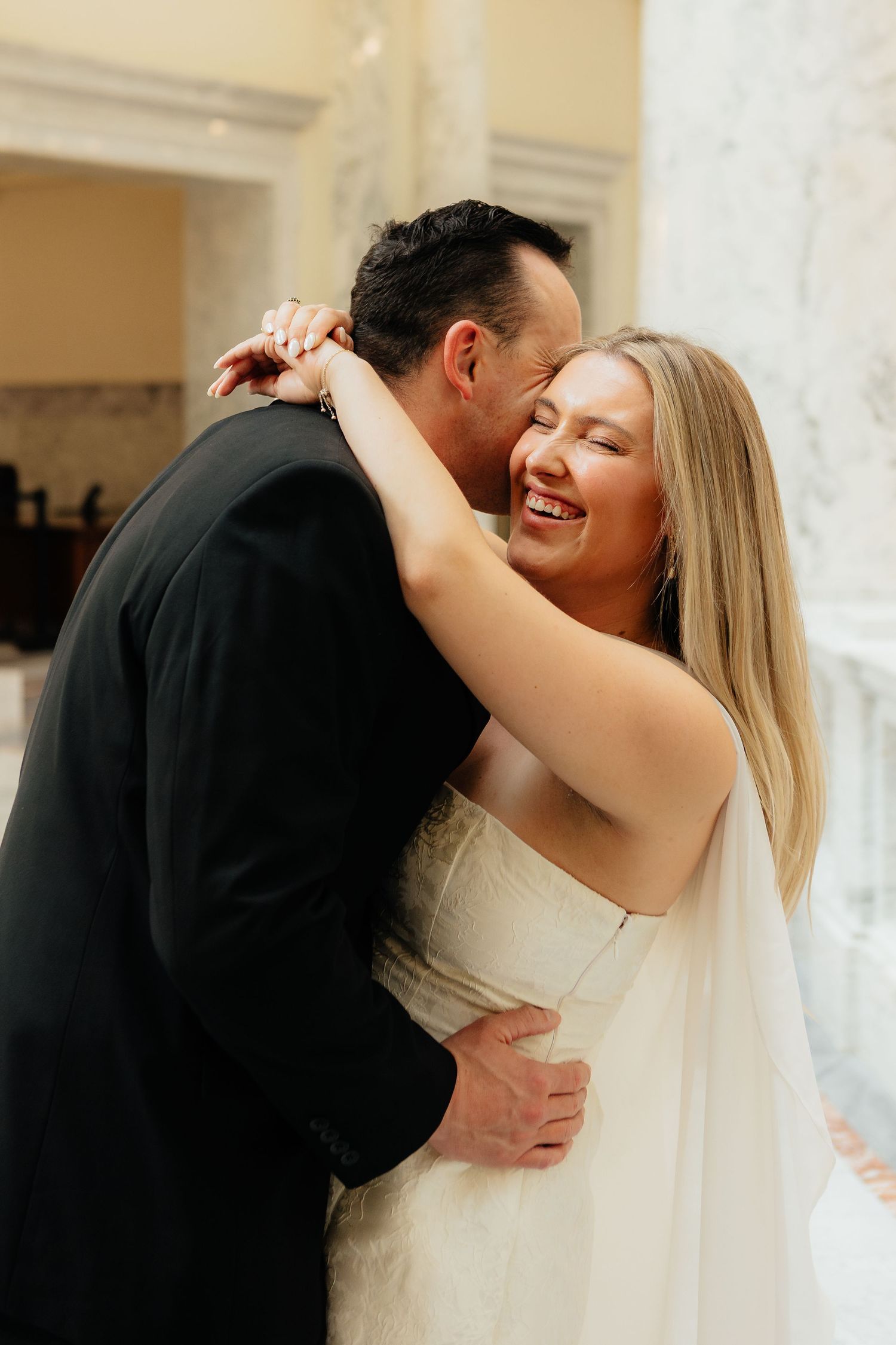 A joyful couple embraces and laughs during an intimate wedding moment captured in a candid portrait.