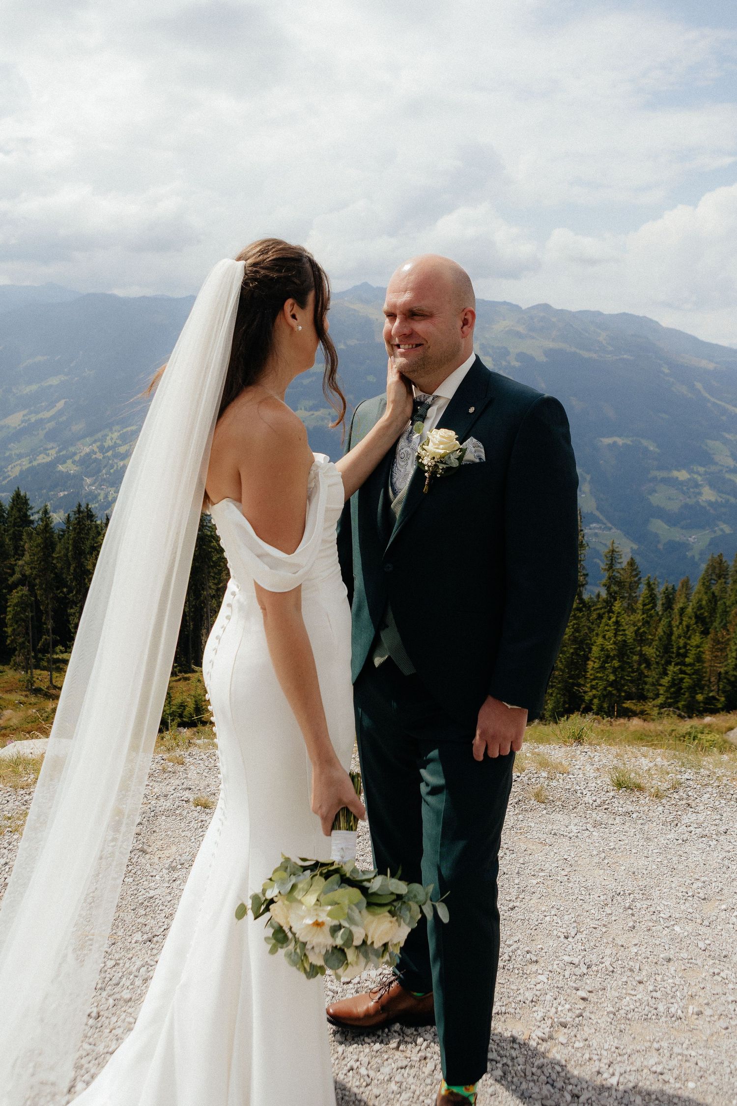 A couple shares an intimate moment against a mountain backdrop during their wedding photoshoot.