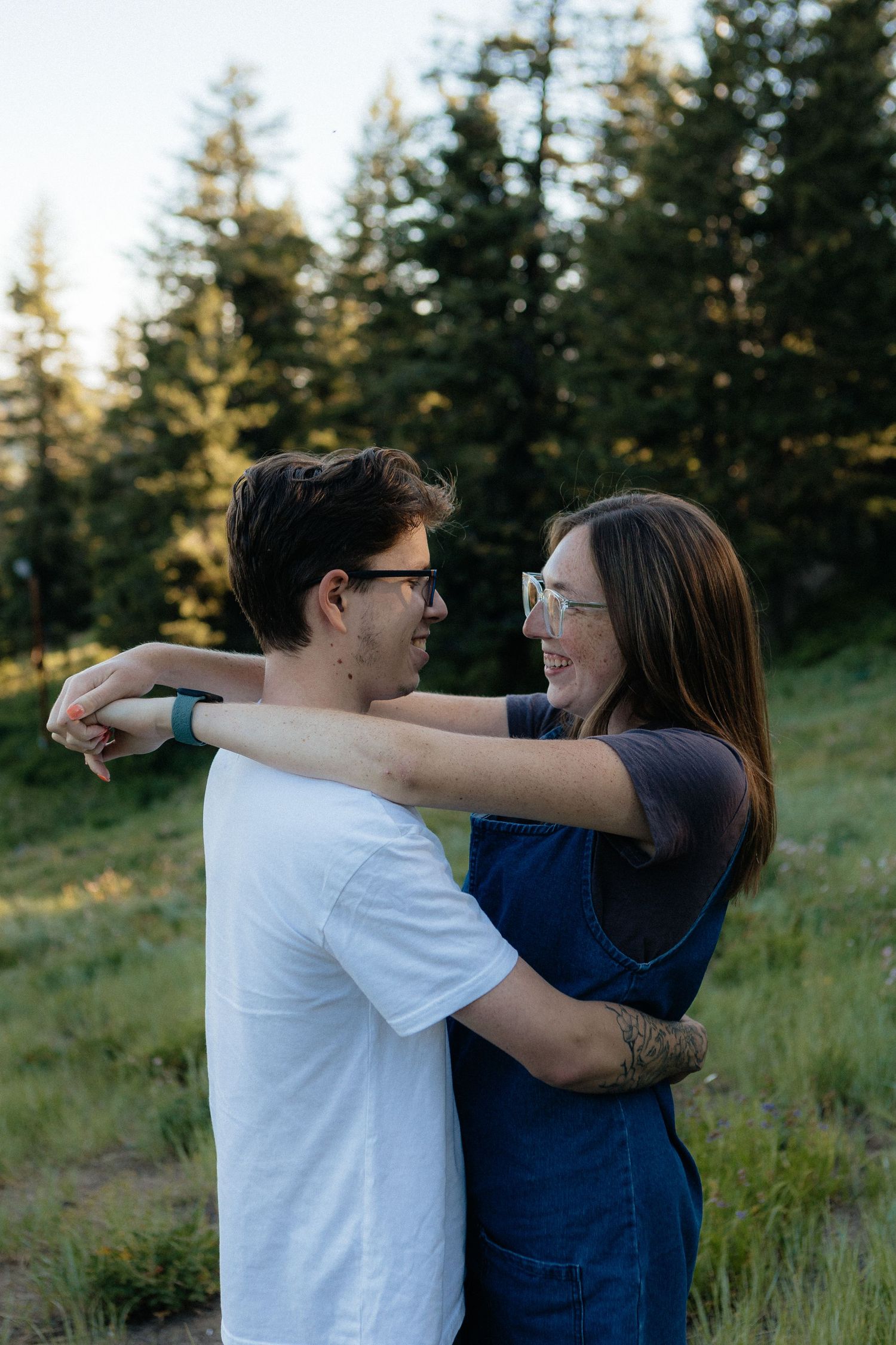 Happy couple embracing in an outdoor forest setting during golden hour.