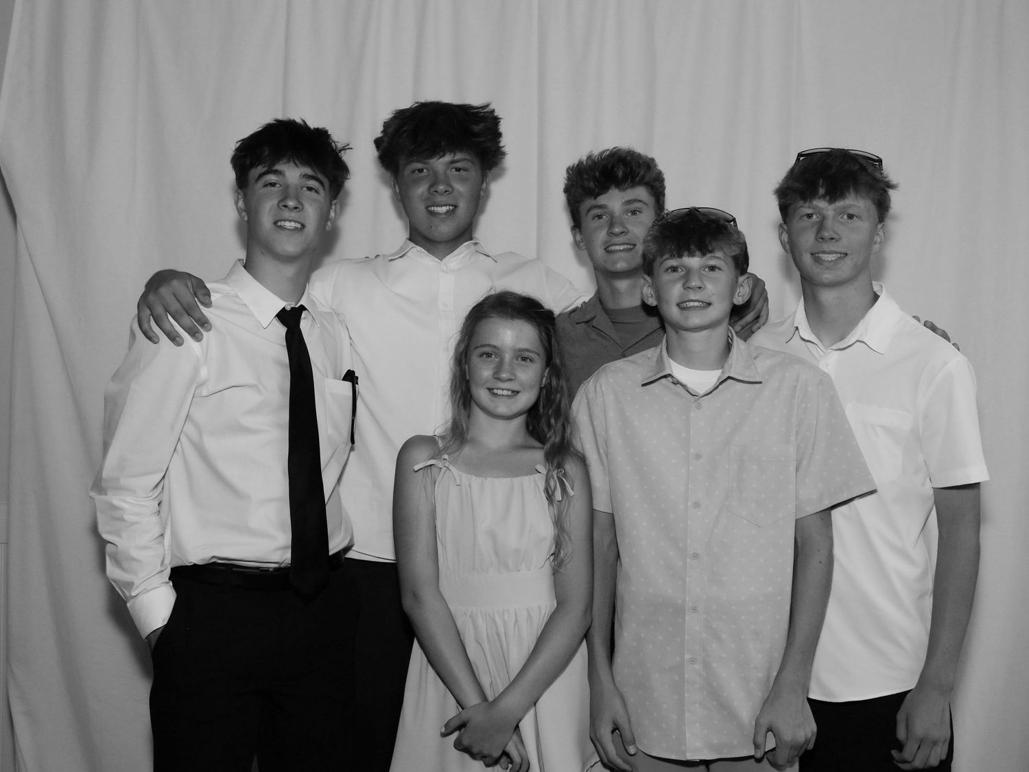 Black and white photo of six teens and a young girl posing together at a formal event.