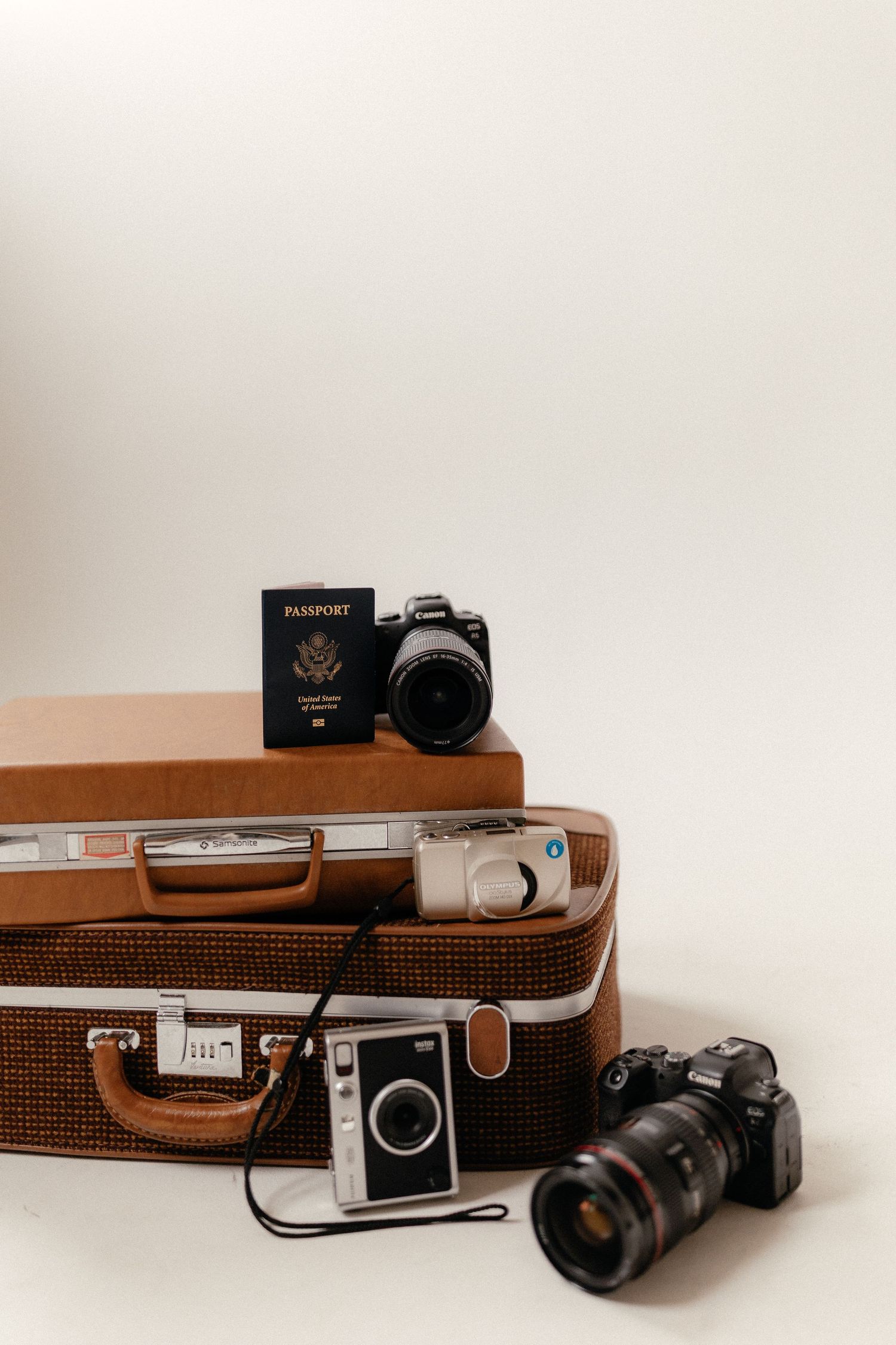 Collection of retro cameras and passport displayed with brown leather suitcase.